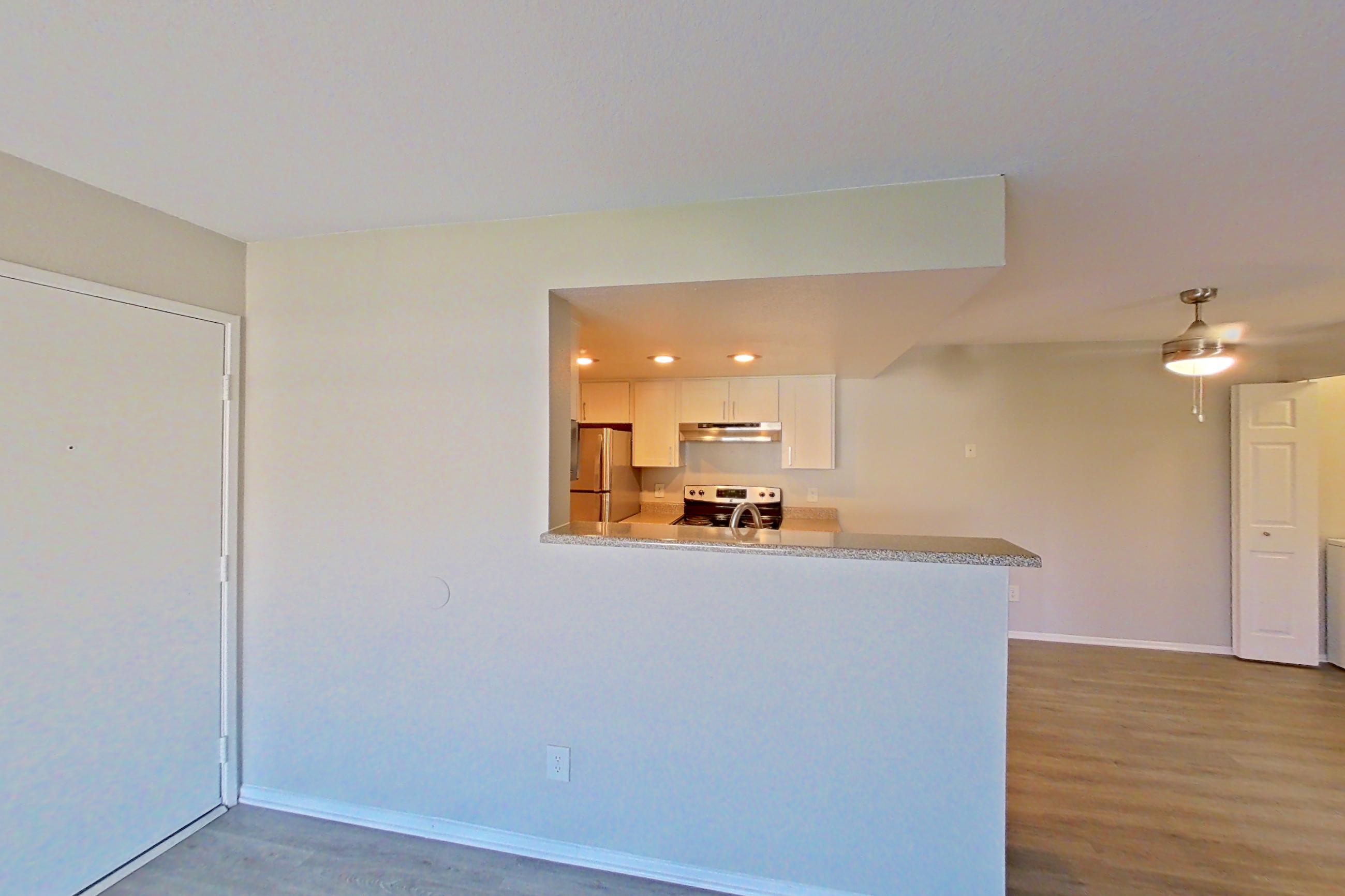 Living room with dark wood-finish flooring and refrigerator, Apartment 11 at Avana Rancho Cucamonga