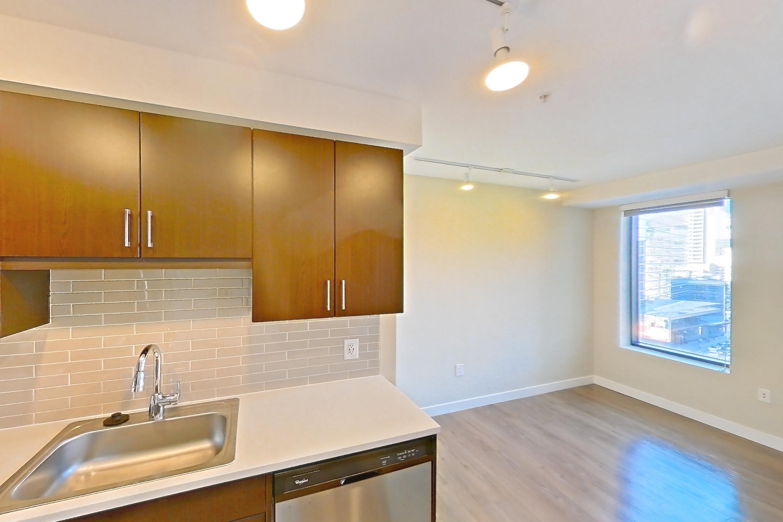 Kitchen with dishwasher, electric range, light countertops, light wood-finish flooring, microwave, oven/range, refrigerator, and stainless steel appliances, Apartment 1007 at Luka