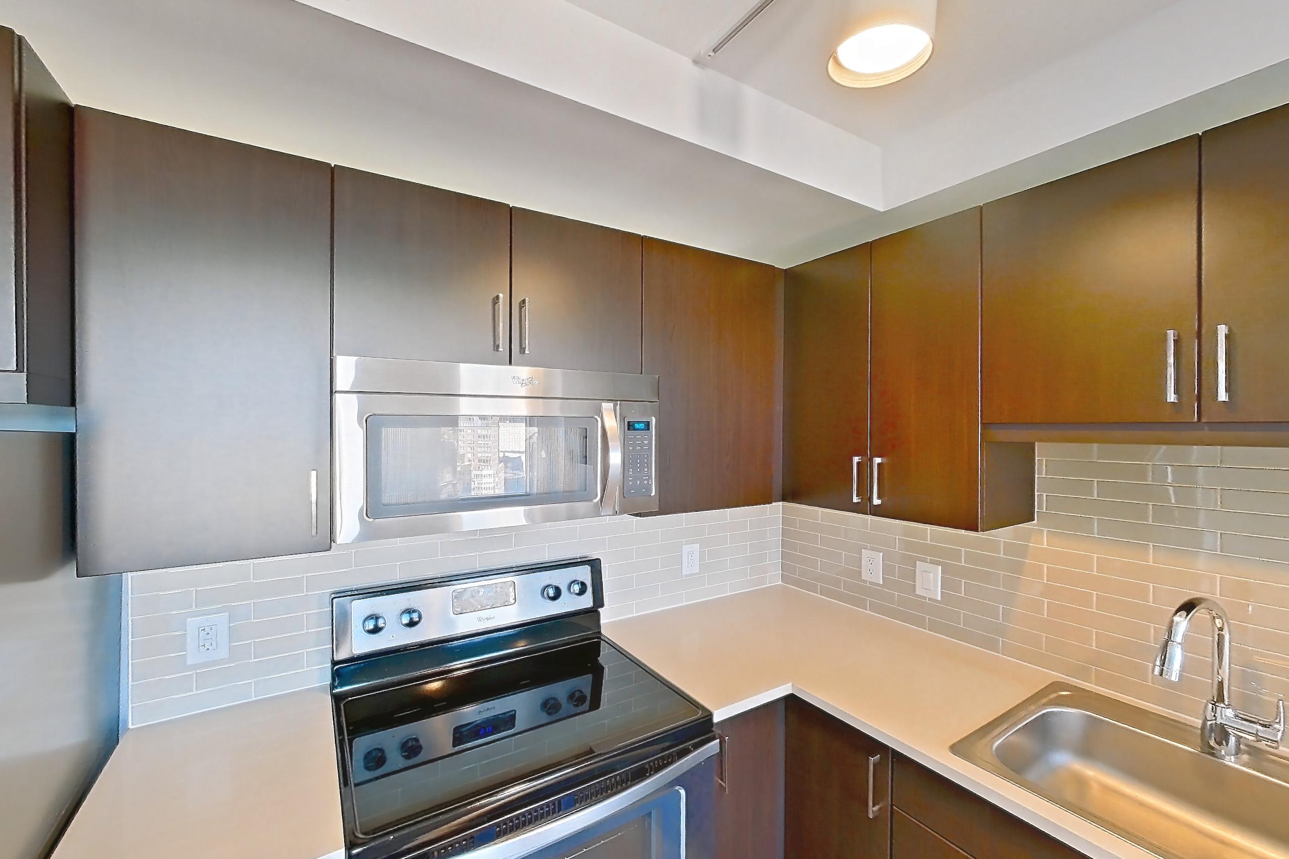 Kitchen with dishwasher, electric range, light countertops, light wood-finish flooring, microwave, oven/range, refrigerator, and stainless steel appliances, Apartment 1807 at Luka