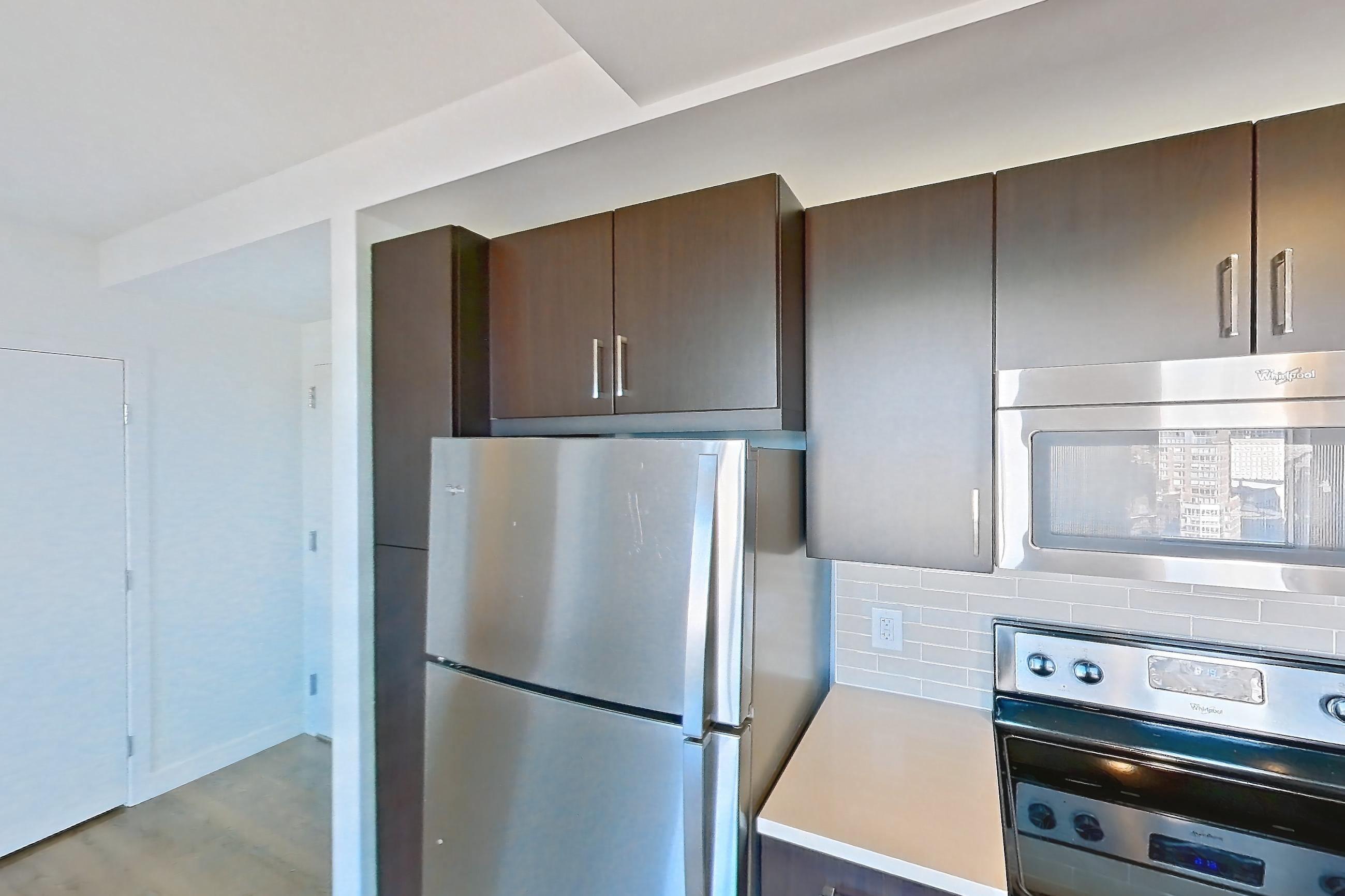 Kitchen with dishwasher, electric range, light countertops, light wood-finish flooring, microwave, oven/range, refrigerator, and stainless steel appliances, Apartment 1807 at Luka