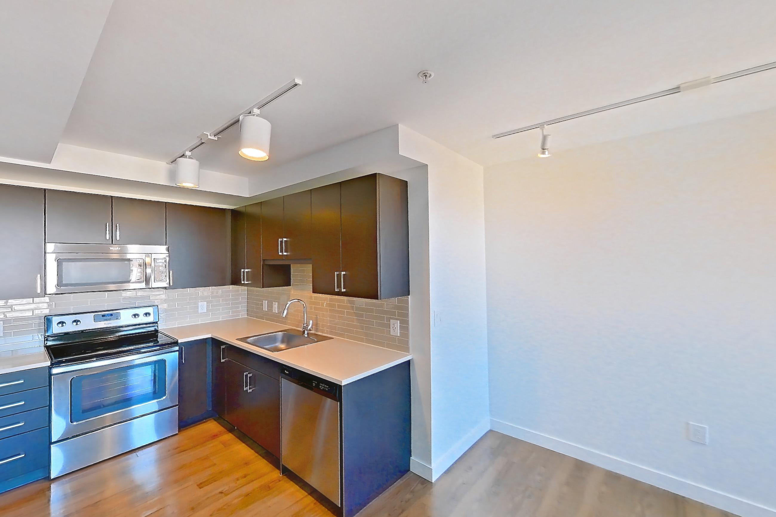 Living room with dark wood-finish flooring, dishwasher, light wood-finish flooring, and stainless steel appliances, Apartment 1807 at Luka