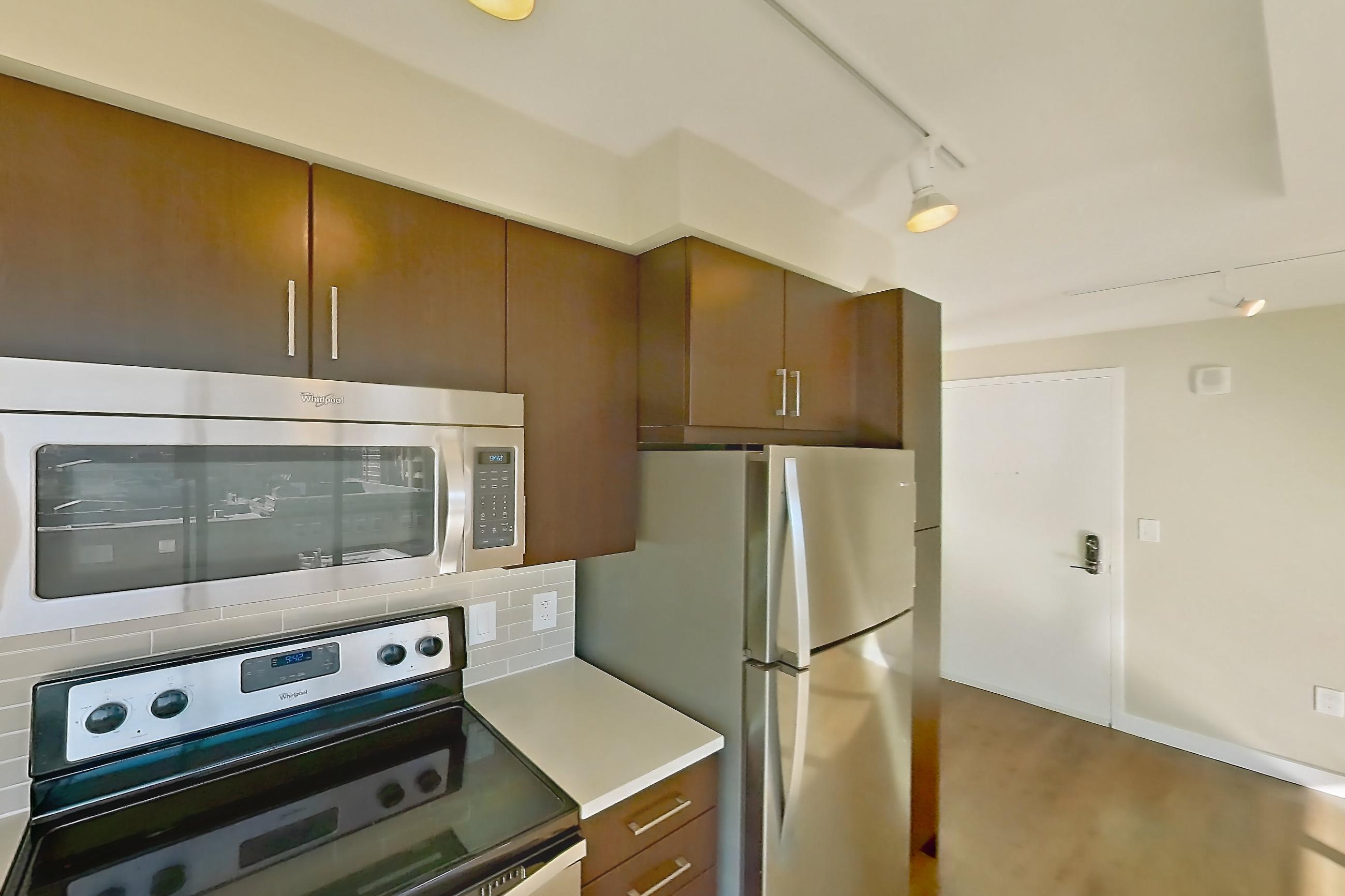 Kitchen with electric range, light countertops, light wood-finish flooring, microwave, oven/range, refrigerator, stainless steel appliances, and white appliances, Apartment 0916 at Luka