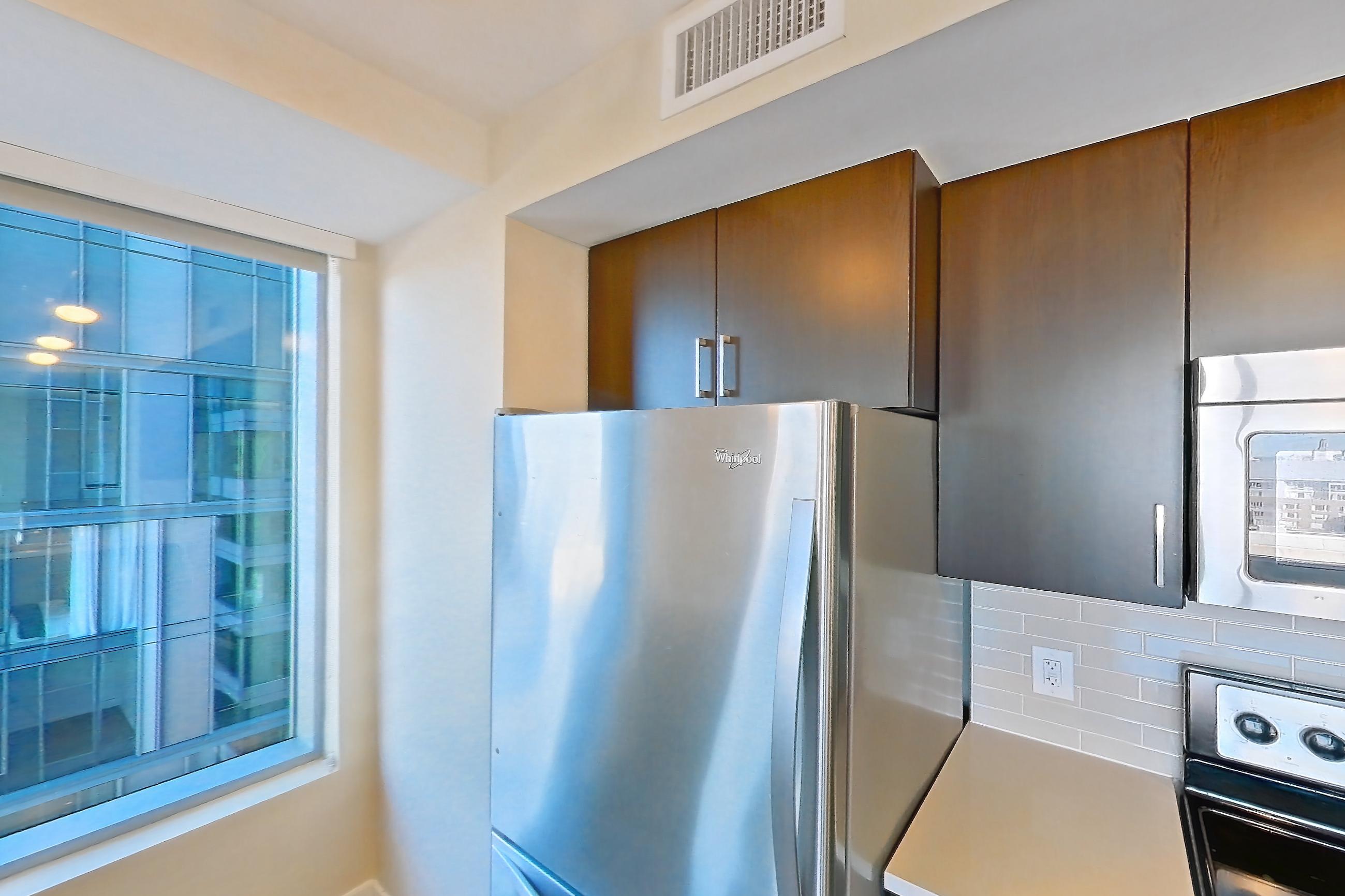 Kitchen with dishwasher, light countertops, light stone countertops, light wood-finish flooring, refrigerator, and stainless steel appliances, Apartment 2101 at Luka