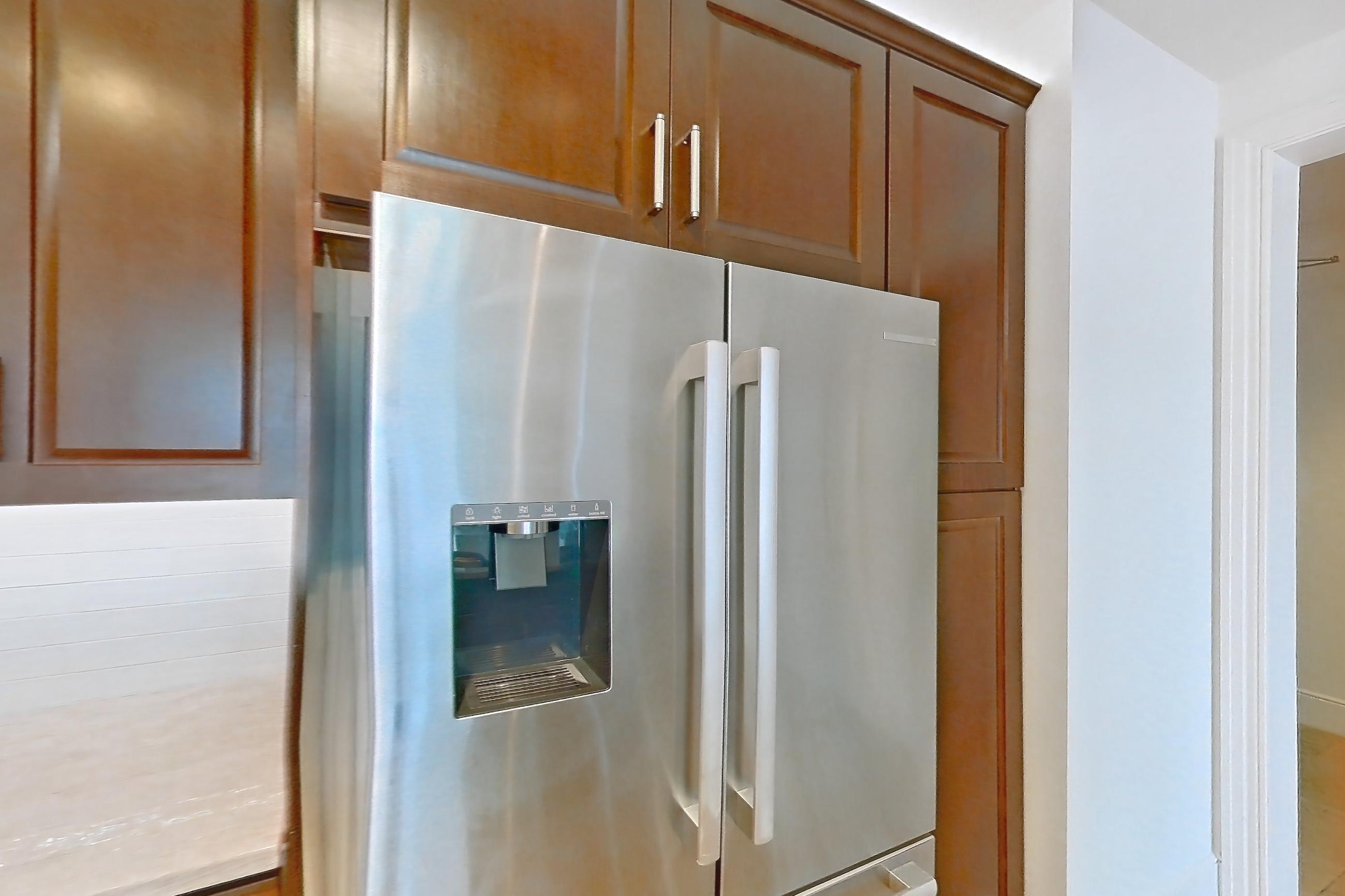 Kitchen with dishwasher, electric range, kitchen island, light countertops, light stone countertops, microwave, oven/range, refrigerator, stainless steel appliances, and water & ice dispenser, Apartment 2008 at Cortland on McKinney