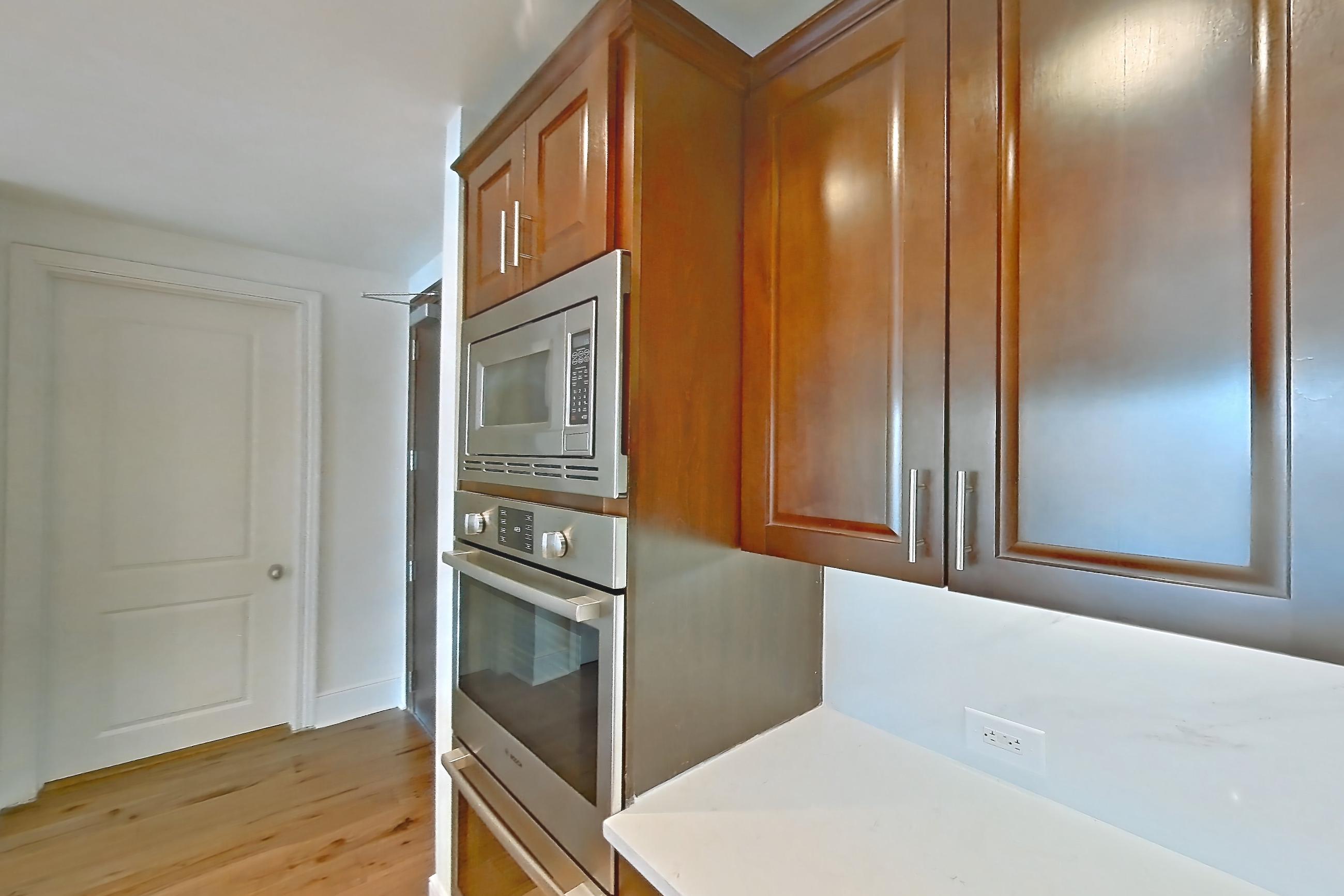 Kitchen with black appliances, cooktop, dishwasher, electric cooktop, light stone countertops, light tile flooring, microwave, oven/range, range hood, refrigerator, stainless steel appliances, and water & ice dispenser, Apartment 1809 at Cortland on McKinney