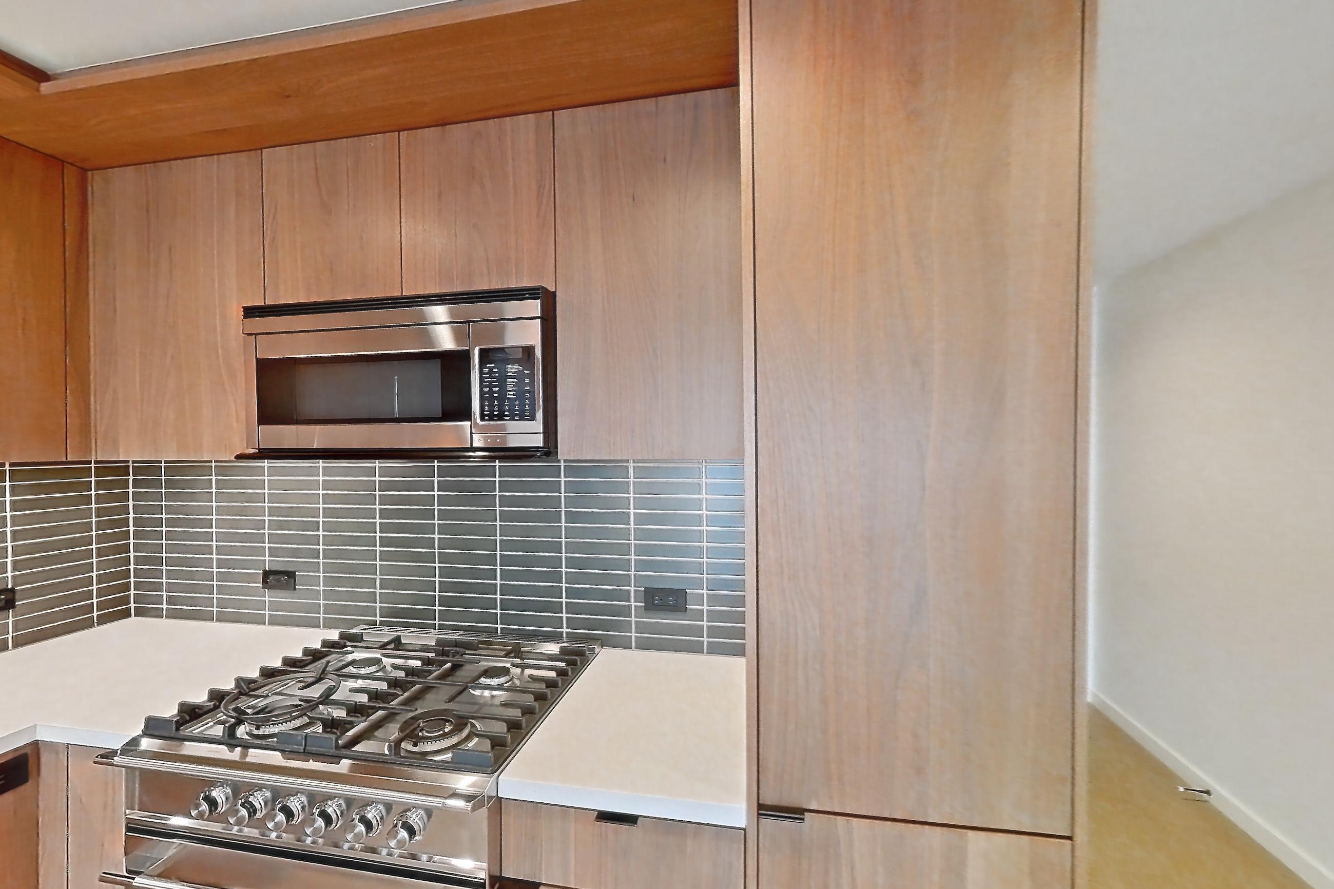 Kitchen with gas range, light stone countertops, light wood-finish flooring, oven/range, and stainless steel appliances, Apartment B-3004 at Beaudry