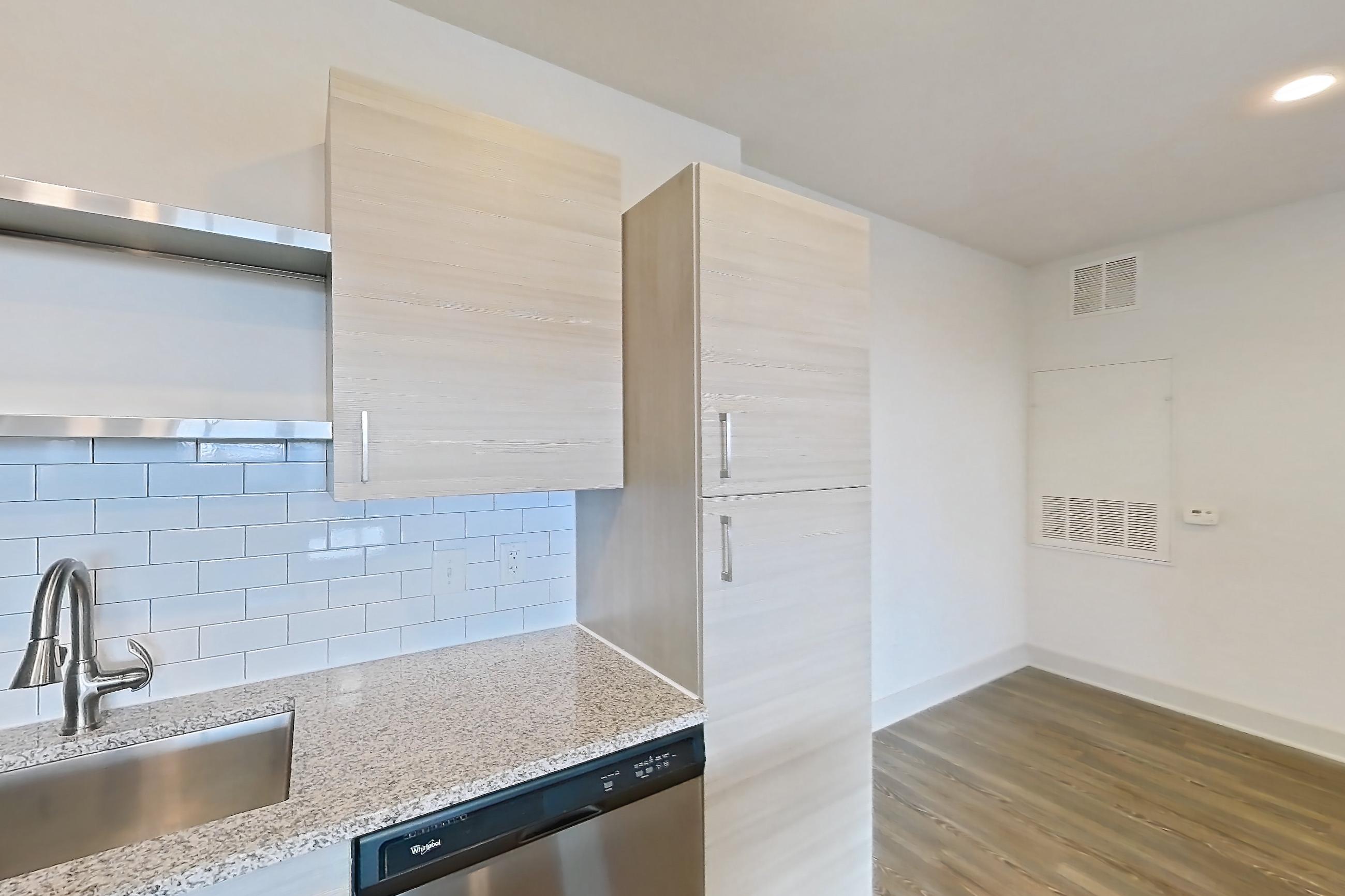Kitchen with dark wood-finish flooring, dishwasher, electric range, light countertops, light stone countertops, oven/range, refrigerator, and stainless steel appliances, Apartment 144-301 at Domain