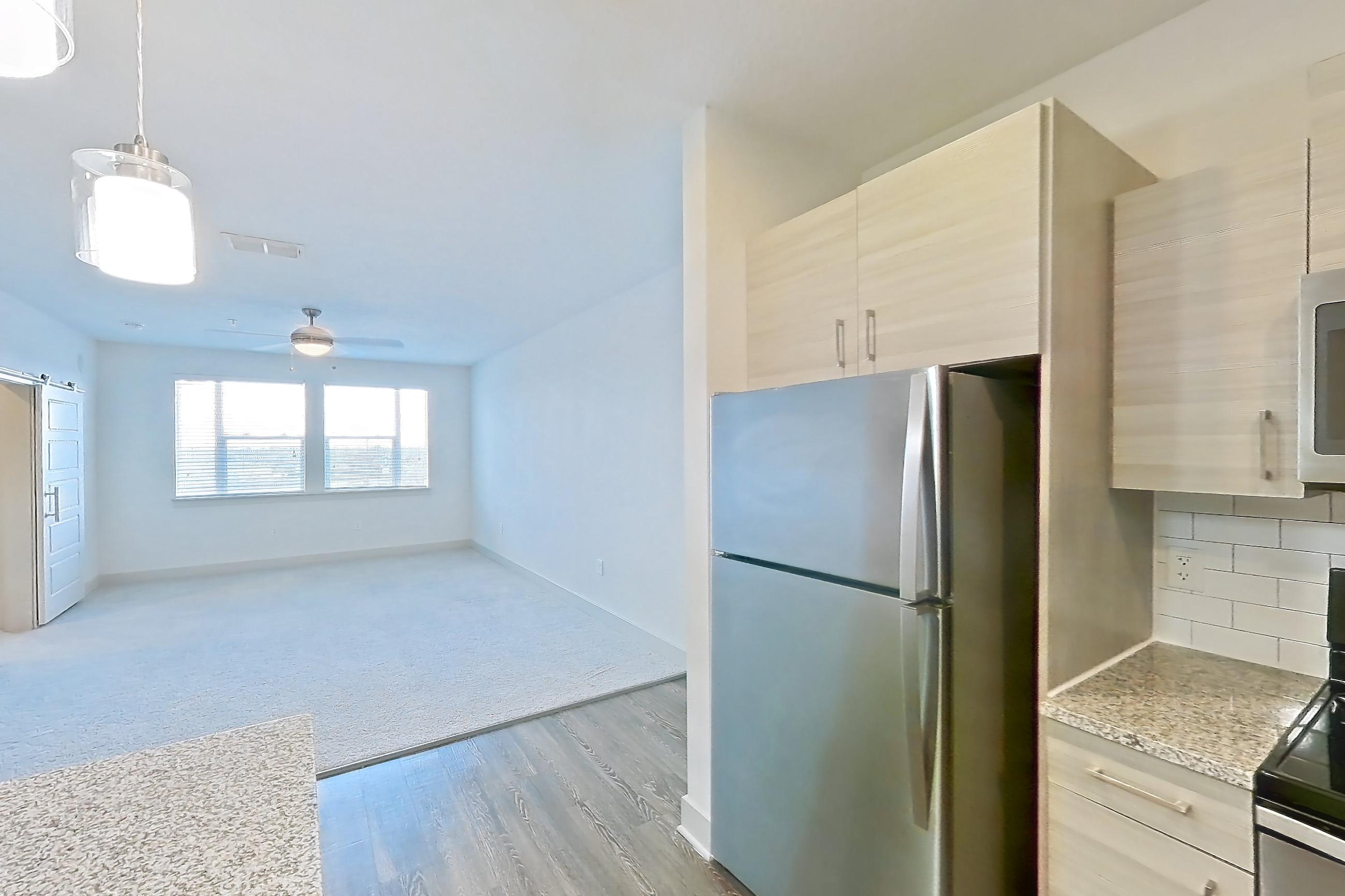 Kitchen with dark wood-finish flooring, dishwasher, electric range, light countertops, light stone countertops, oven/range, refrigerator, and stainless steel appliances, Apartment 144-301 at Domain