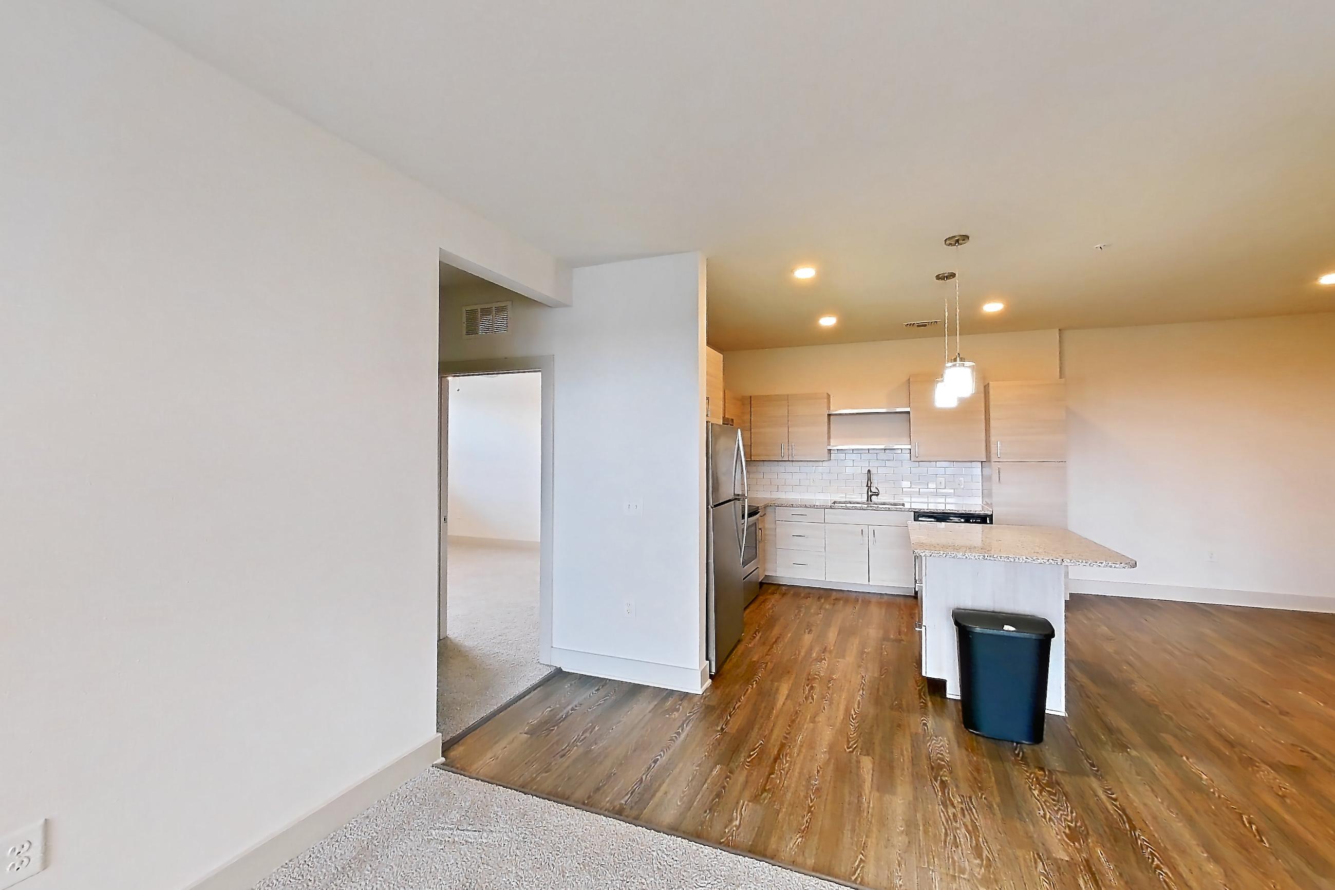 Living room with dark carpet, light stone countertops, oven/range, and stainless steel appliances, Apartment 144-301 at Domain