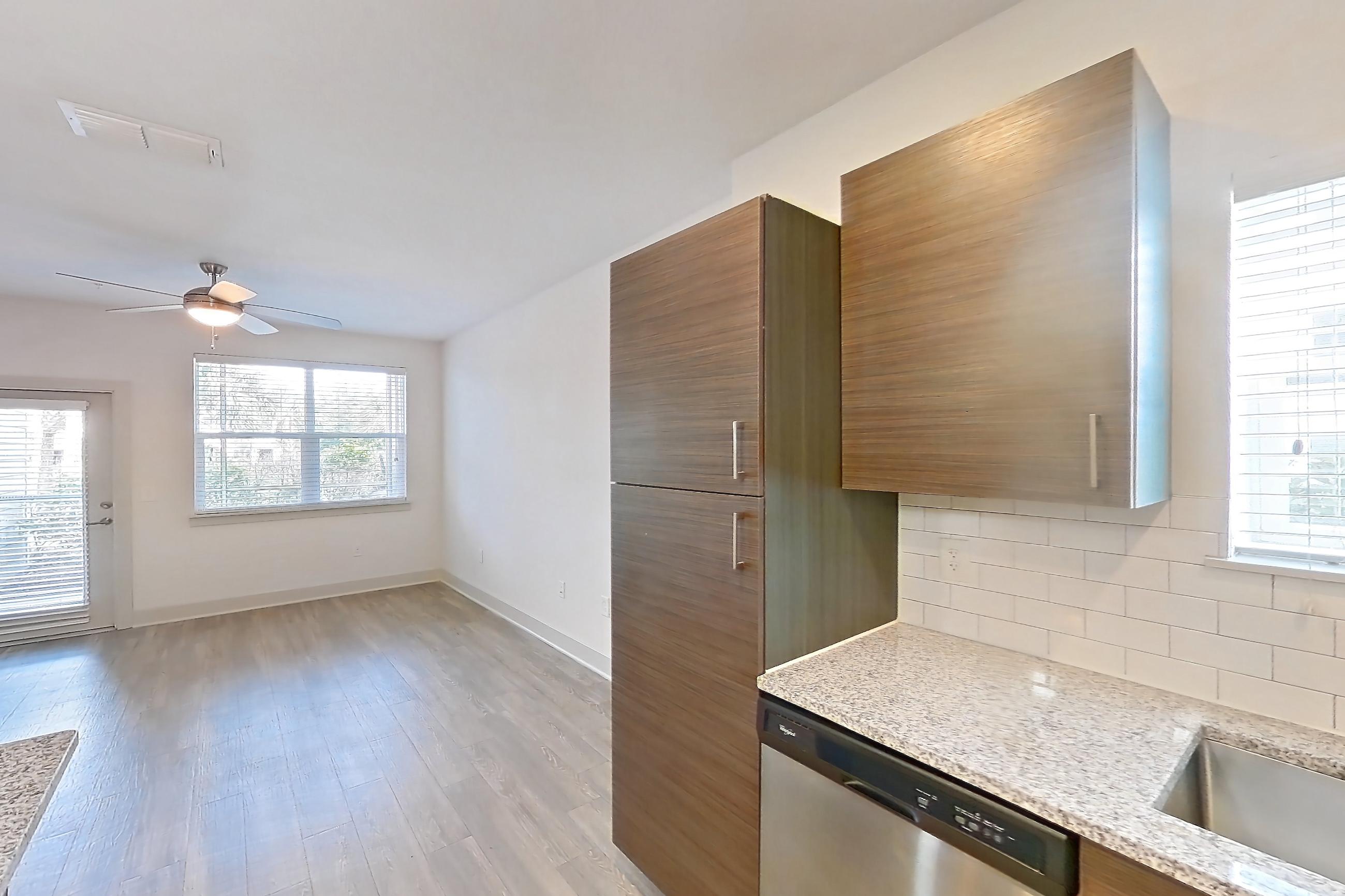 Kitchen with dishwasher, light stone countertops, light wood-finish flooring, oven/range, refrigerator, and stainless steel appliances, Apartment 150-104 at Domain