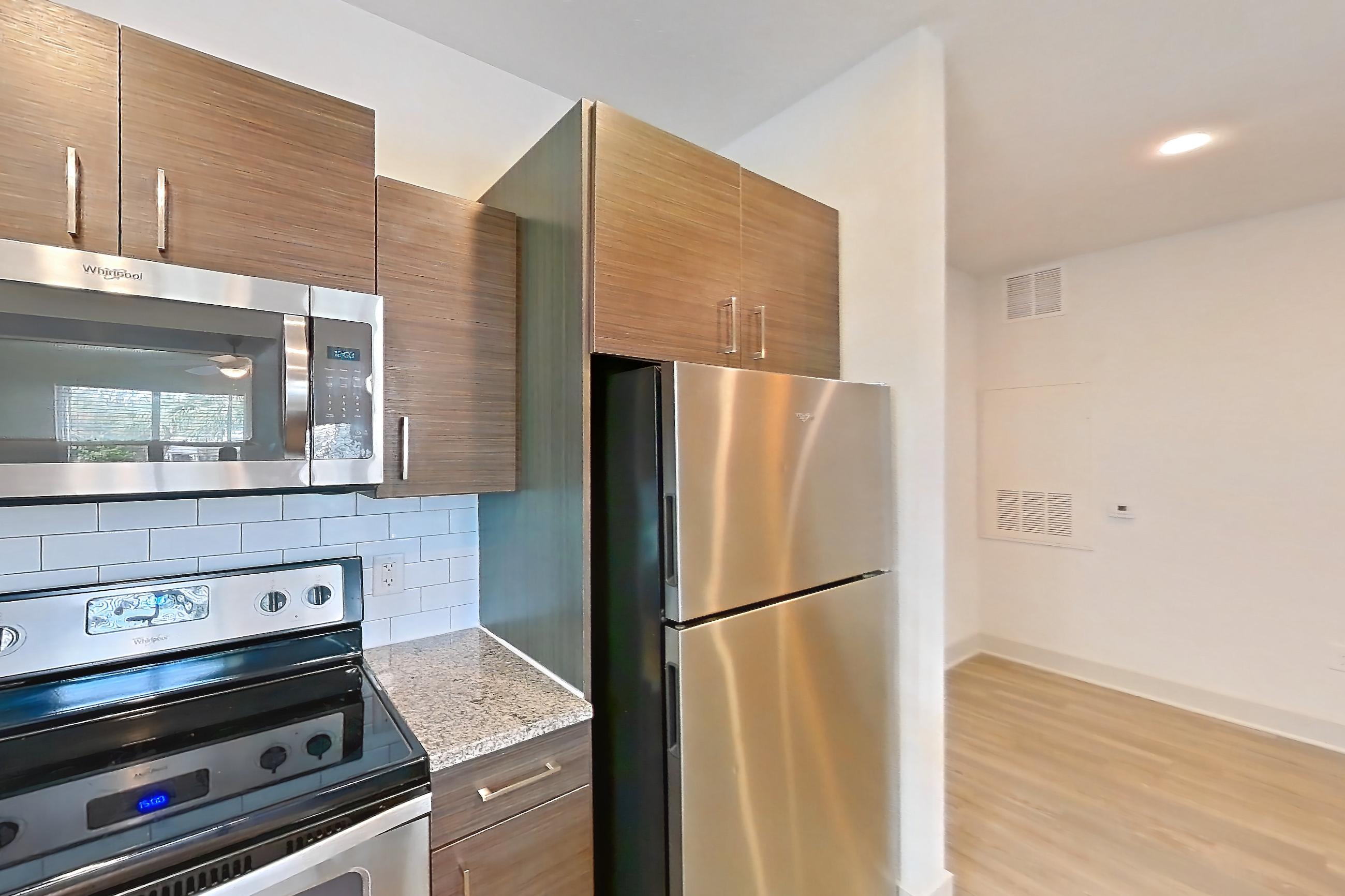 Kitchen with dishwasher, light stone countertops, light wood-finish flooring, oven/range, refrigerator, and stainless steel appliances, Apartment 150-104 at Domain
