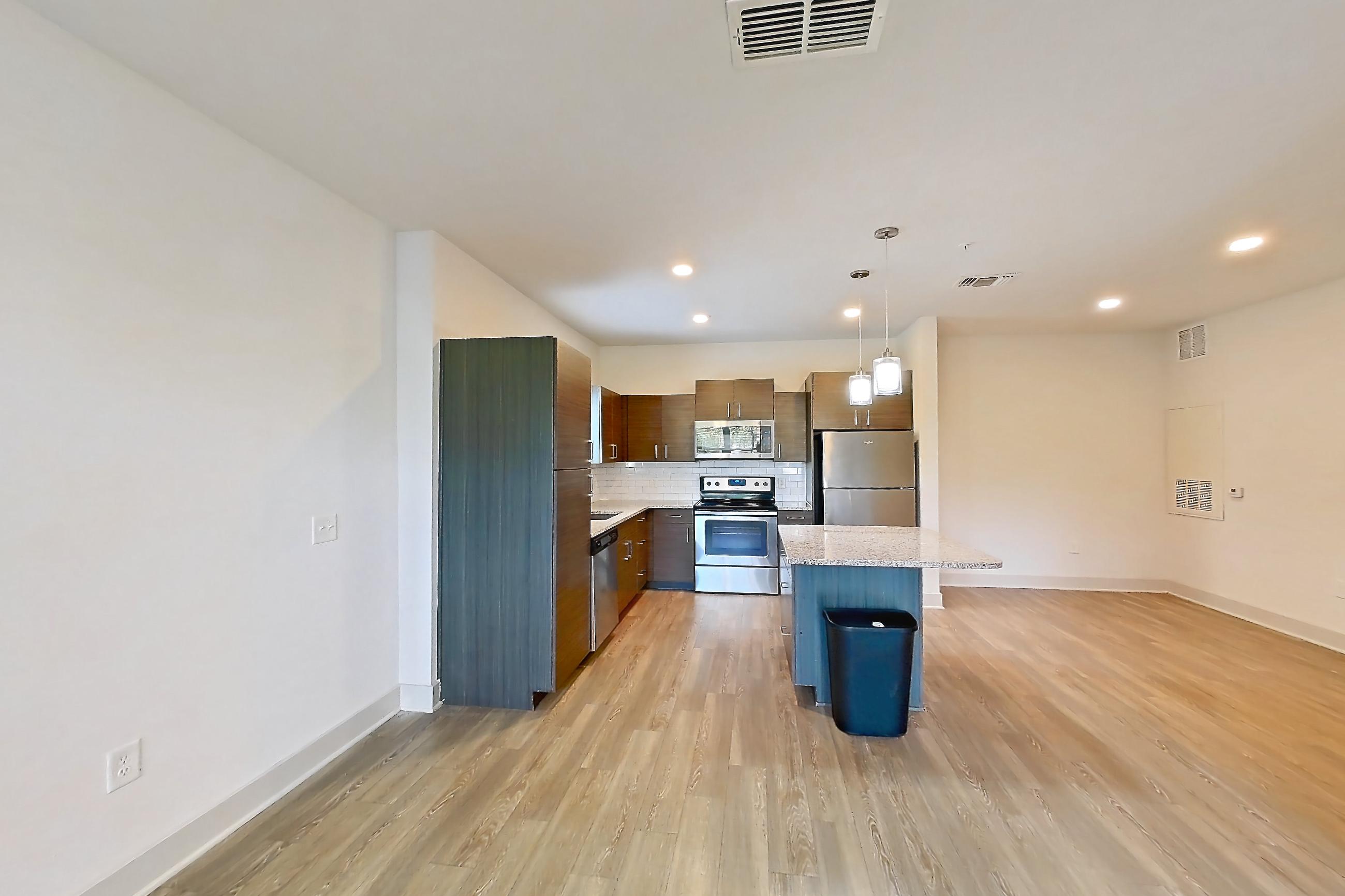 Living room with dark wood-finish flooring, dishwasher, electric range, light stone countertops, light wood-finish flooring, oven/range, refrigerator, and stainless steel appliances, Apartment 150-104 at Domain