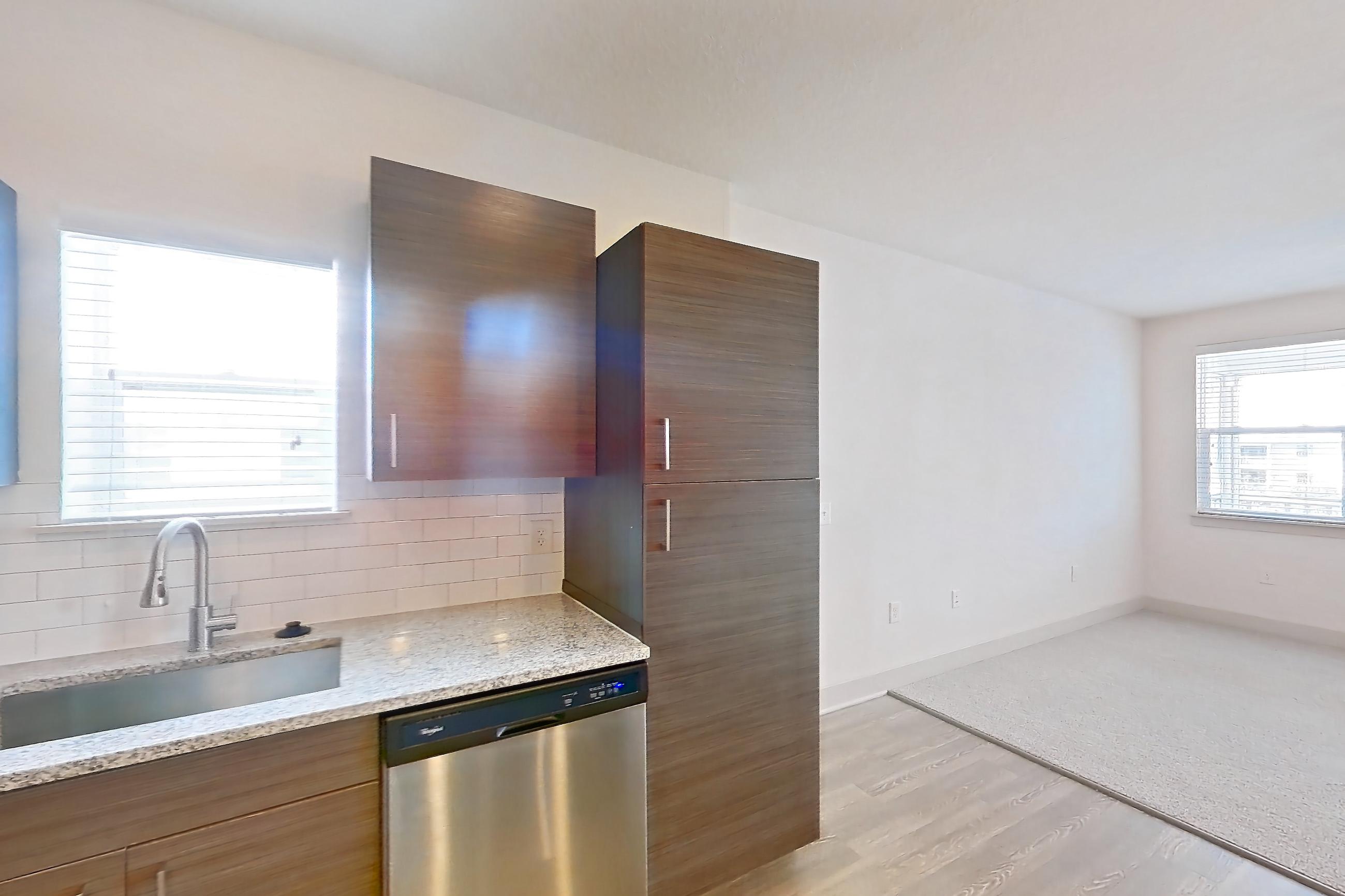 Kitchen with dishwasher, light stone countertops, light wood-finish flooring, refrigerator, and stainless steel appliances, Apartment 156-303 at Domain