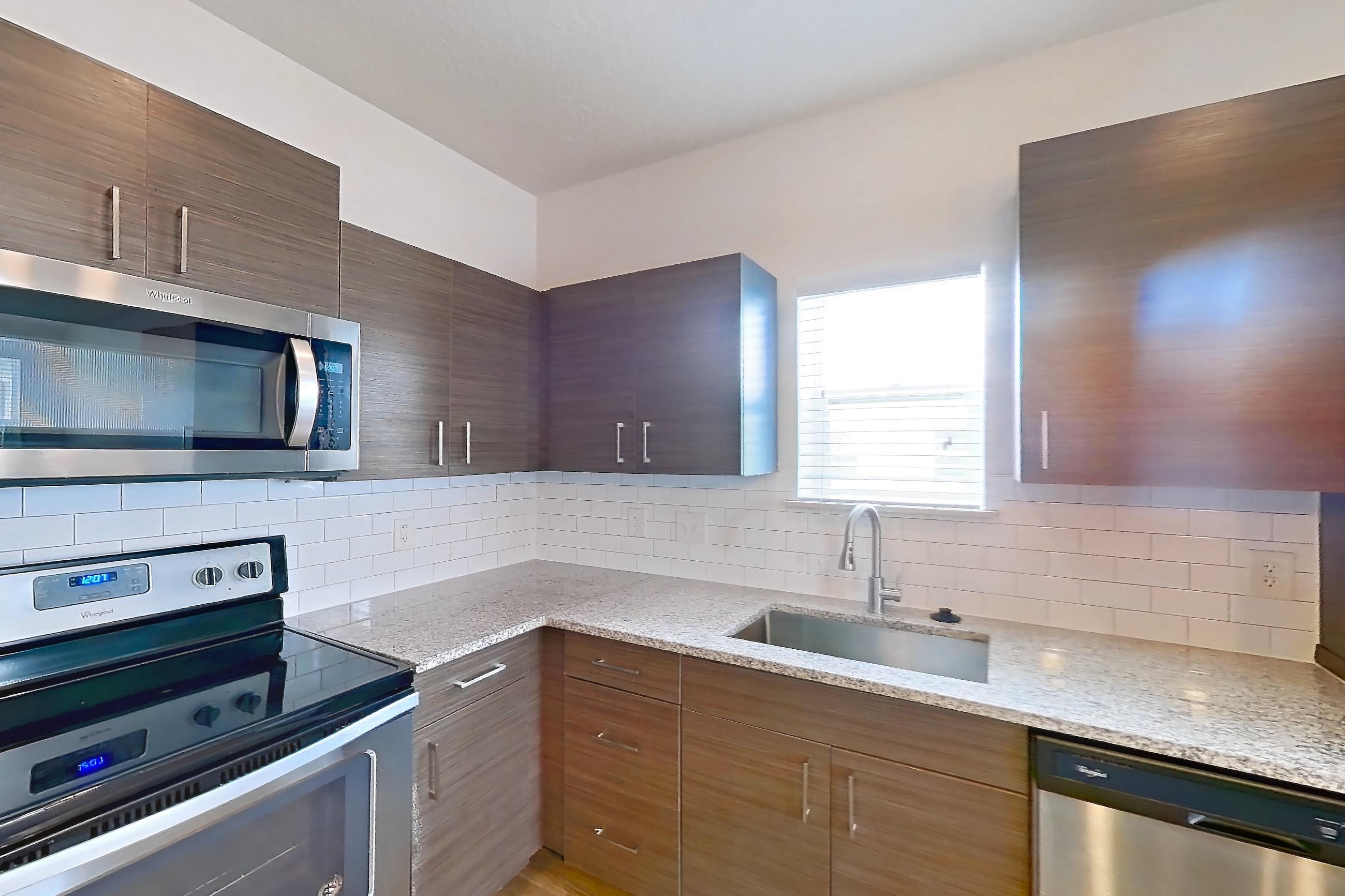 Kitchen with dishwasher, light stone countertops, light wood-finish flooring, refrigerator, and stainless steel appliances, Apartment 156-303 at Domain