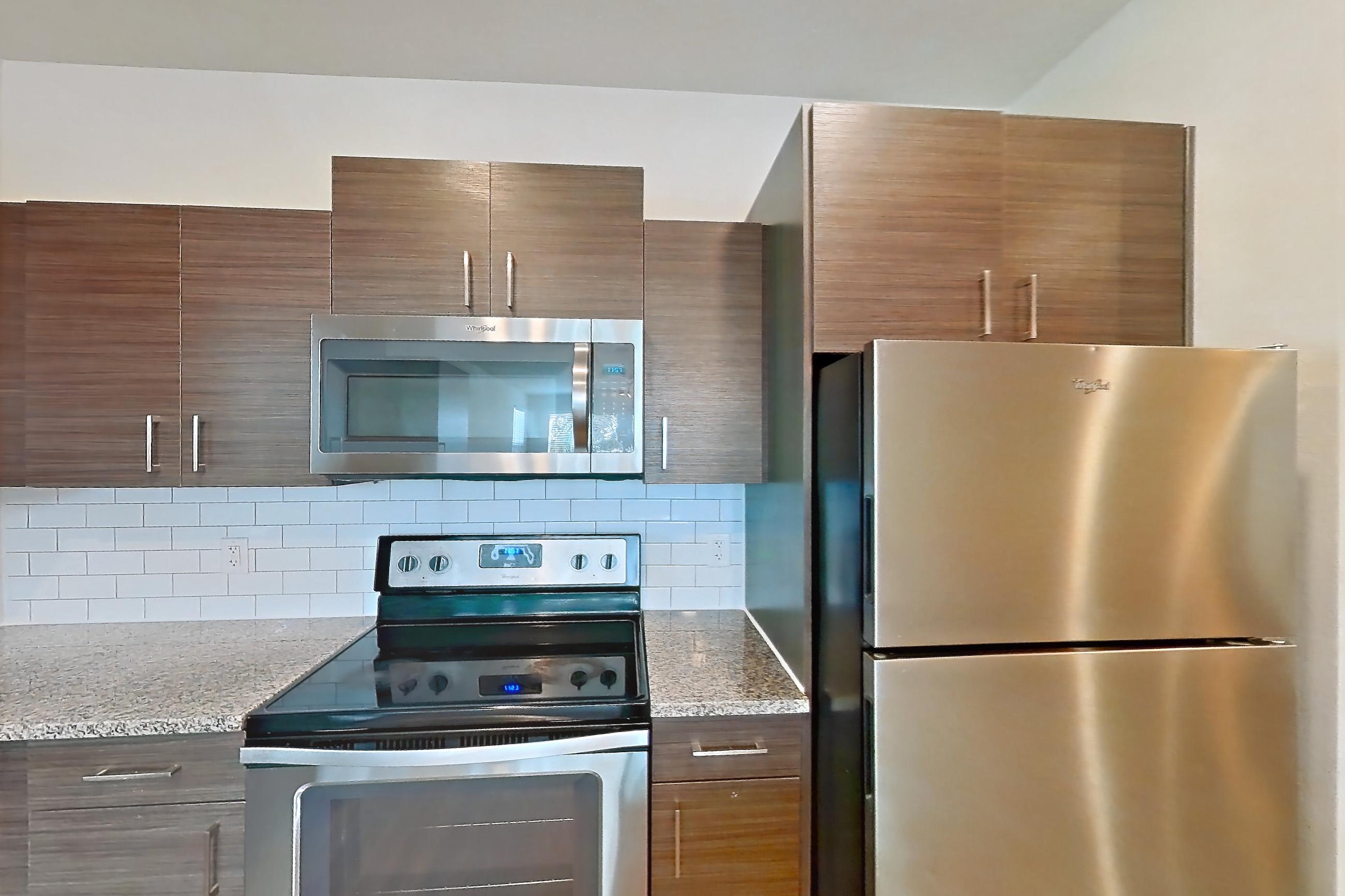 Kitchen with dishwasher, electric range, light stone countertops, light wood-finish flooring, microwave, oven/range, refrigerator, and stainless steel appliances, Apartment 148-201 at Domain