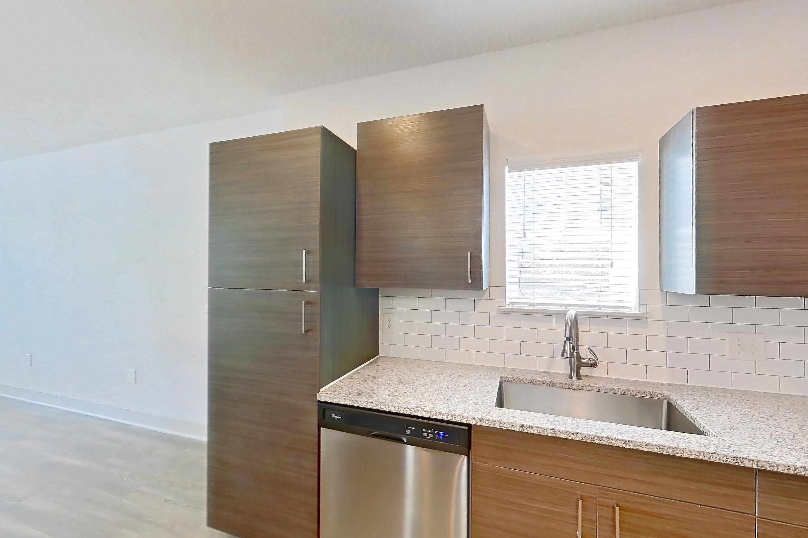 Kitchen with dishwasher, light stone countertops, light wood-finish flooring, oven/range, refrigerator, and stainless steel appliances, Apartment 156-101 at Domain