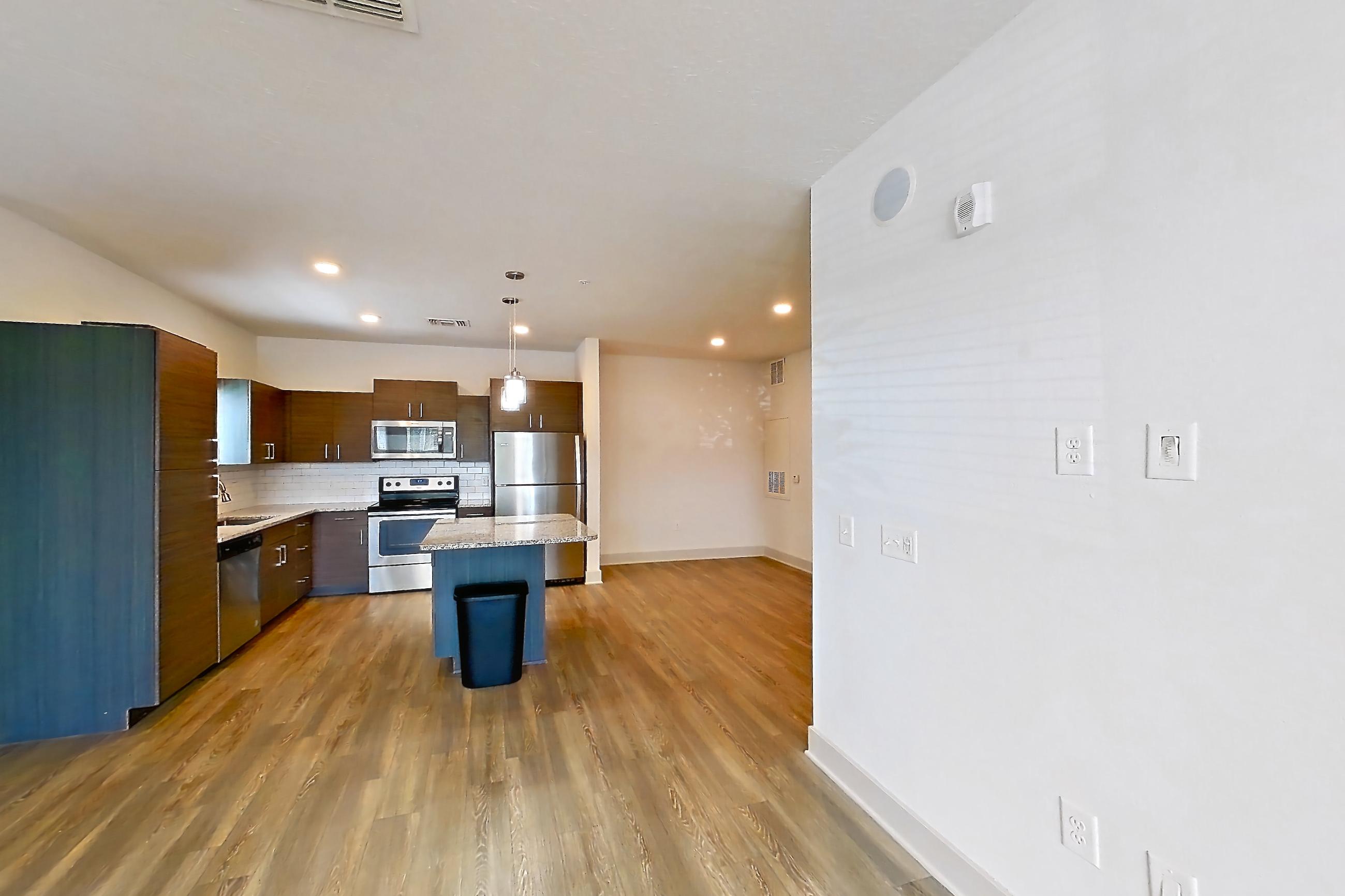 Living room with dark wood-finish flooring, electric range, light stone countertops, oven/range, refrigerator, and stainless steel appliances, Apartment 156-101 at Domain