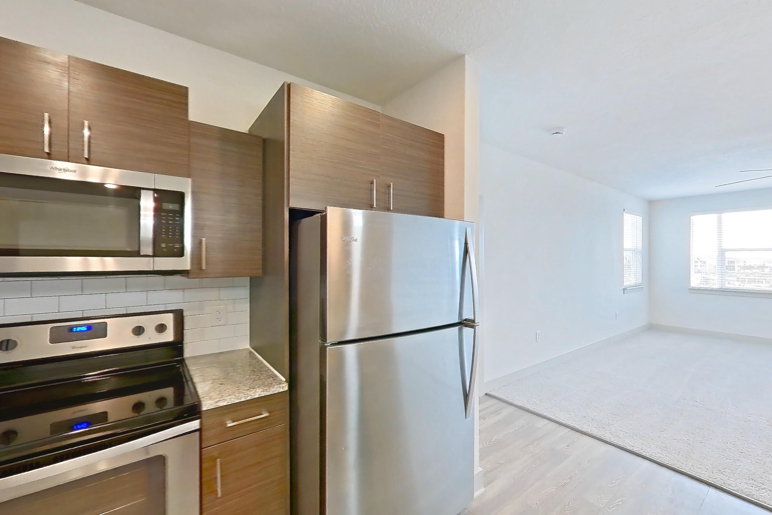 Kitchen with electric range, light stone countertops, light wood-finish flooring, microwave, oven/range, refrigerator, and stainless steel appliances, Apartment 148-302 at Domain