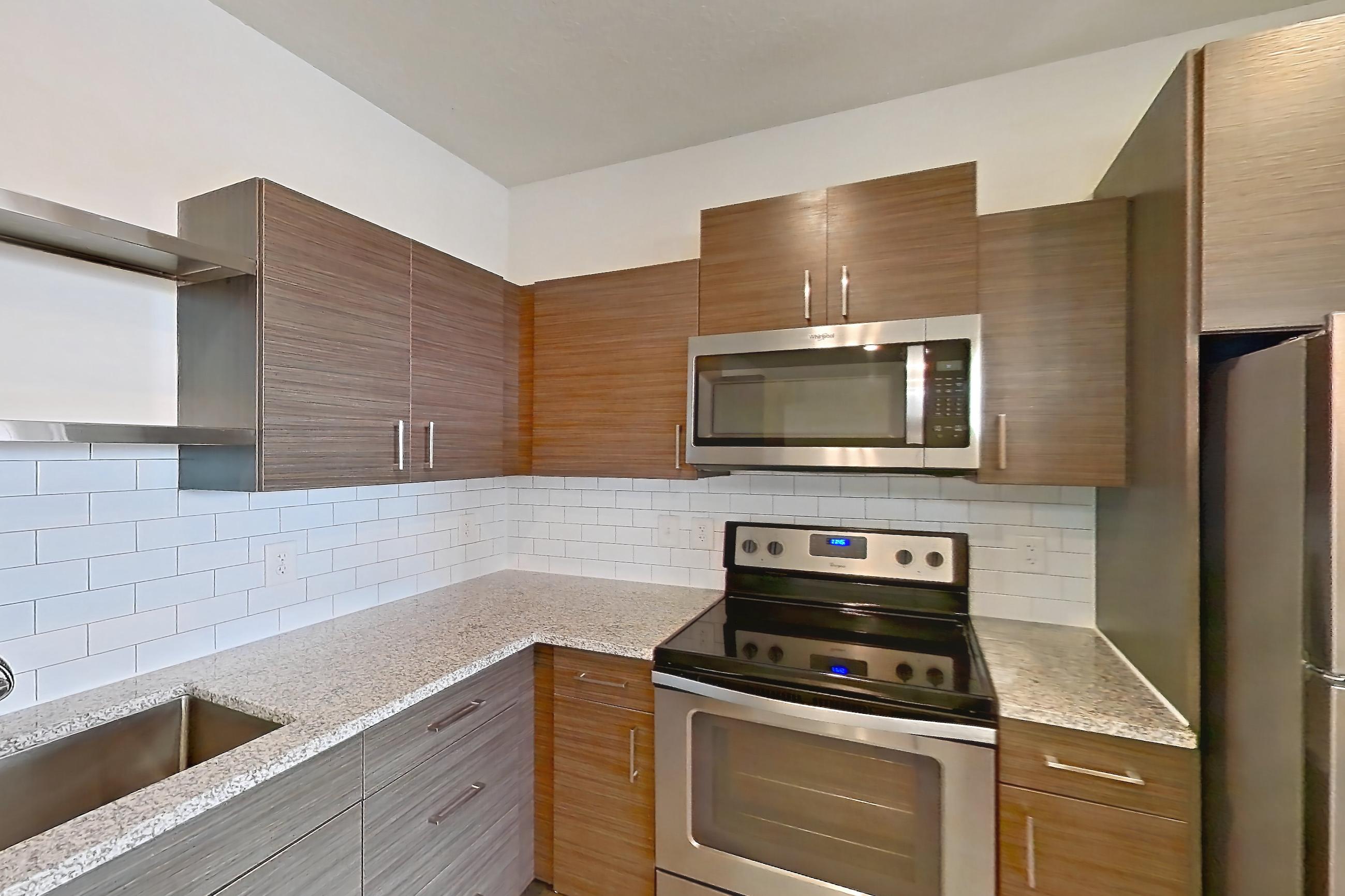 Kitchen with electric range, light stone countertops, light wood-finish flooring, microwave, oven/range, refrigerator, and stainless steel appliances, Apartment 148-302 at Domain