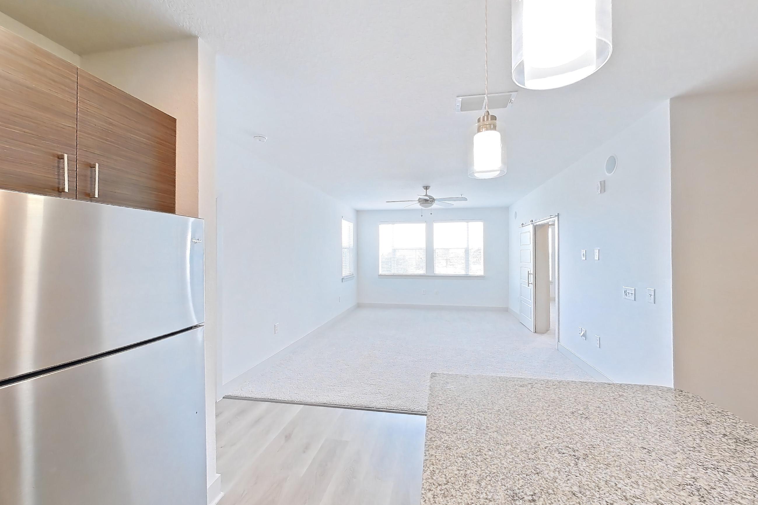 Kitchen with electric range, light stone countertops, light wood-finish flooring, microwave, oven/range, refrigerator, and stainless steel appliances, Apartment 156-202 at Domain