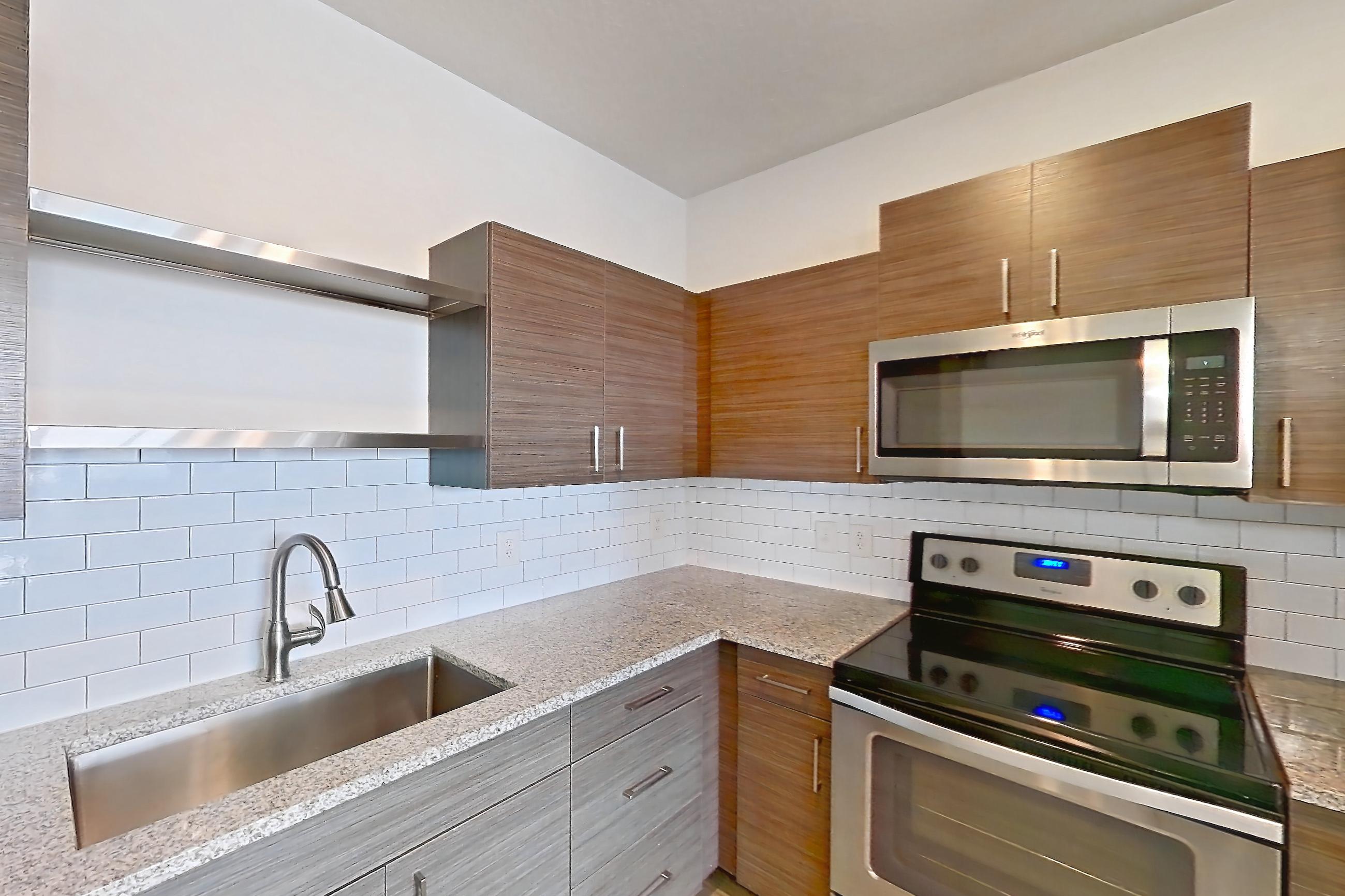 Kitchen with electric range, light stone countertops, light wood-finish flooring, microwave, oven/range, refrigerator, and stainless steel appliances, Apartment 156-202 at Domain