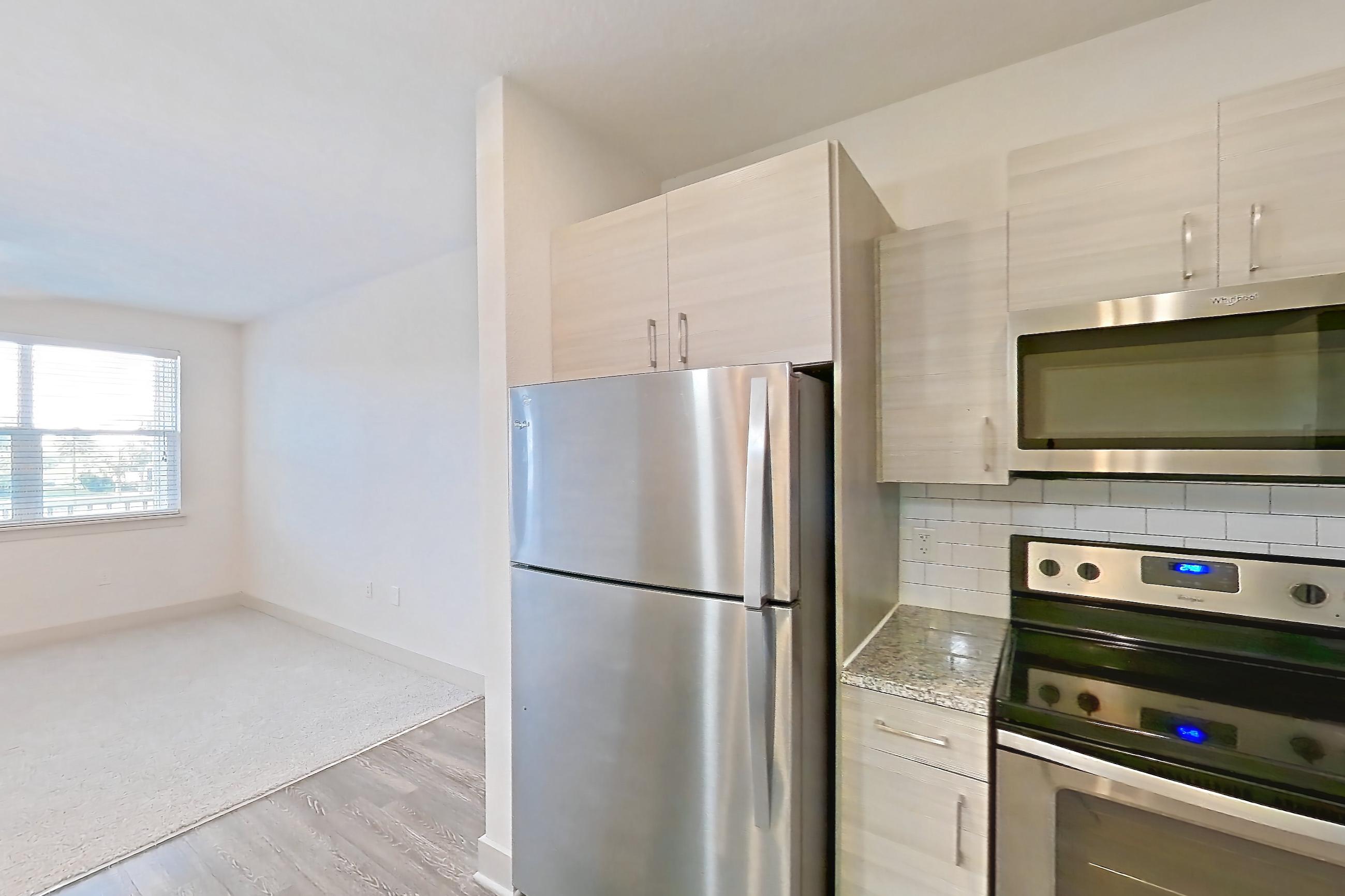 Kitchen with dark wood-finish flooring, dishwasher, electric range, light countertops, light stone countertops, microwave, oven/range, refrigerator, and stainless steel appliances, Apartment 154-204 at Domain