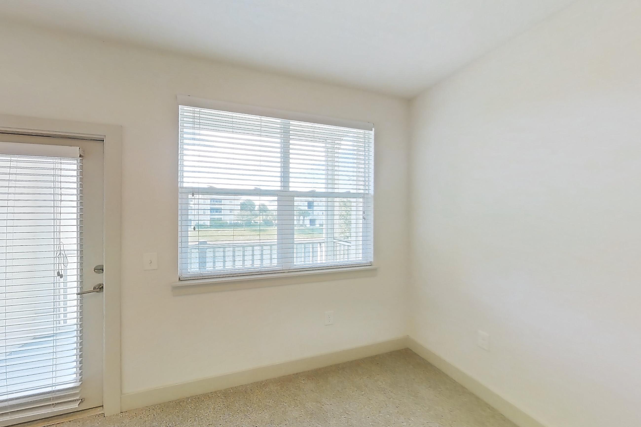 Living room with dark wood-finish flooring, light carpet, light stone countertops, refrigerator, and stainless steel appliances, Apartment 154-204 at Domain