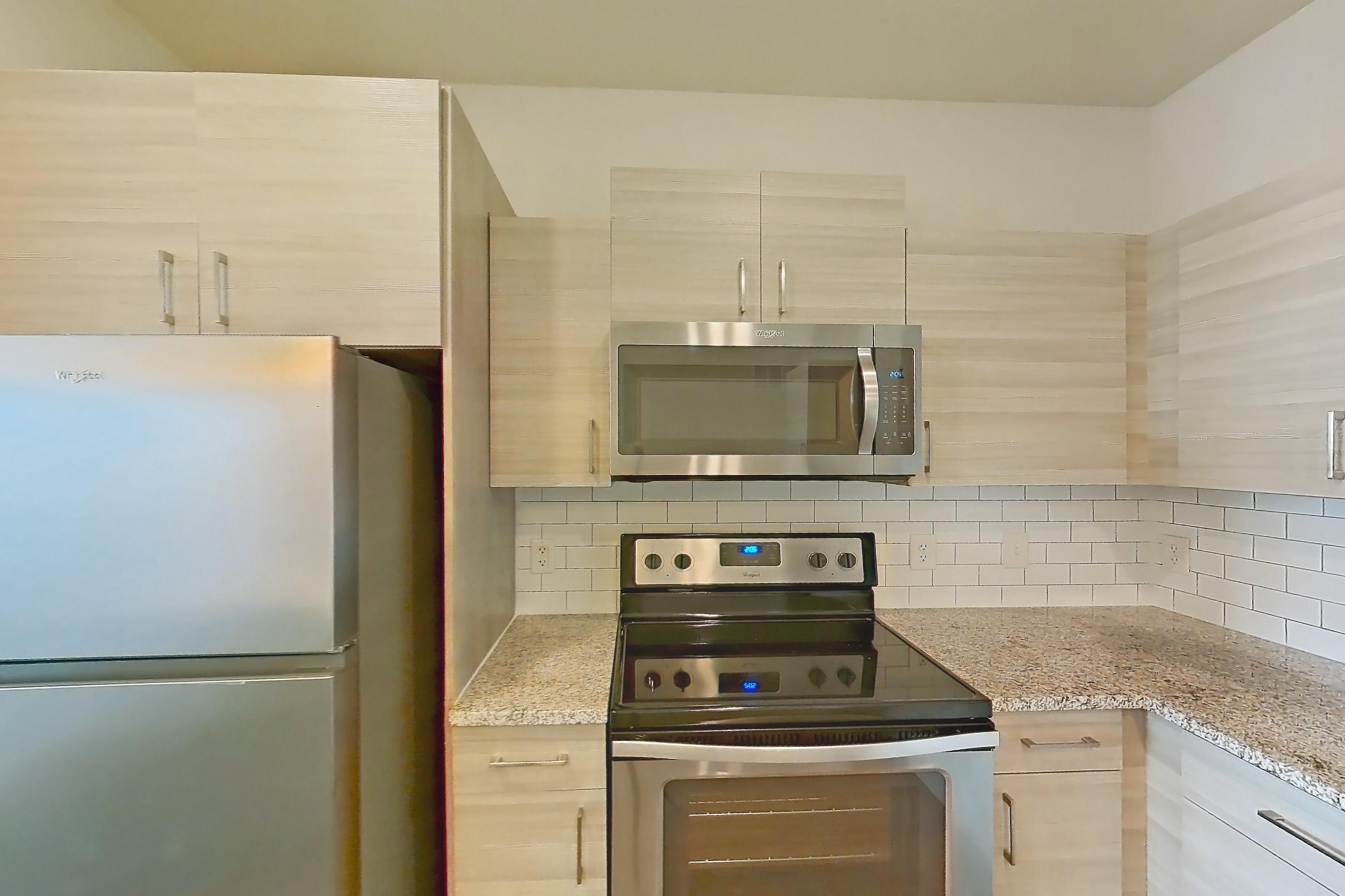 Kitchen with dishwasher, electric range, light countertops, light stone countertops, light wood-finish flooring, oven/range, refrigerator, and stainless steel appliances, Apartment 114-301 at Domain