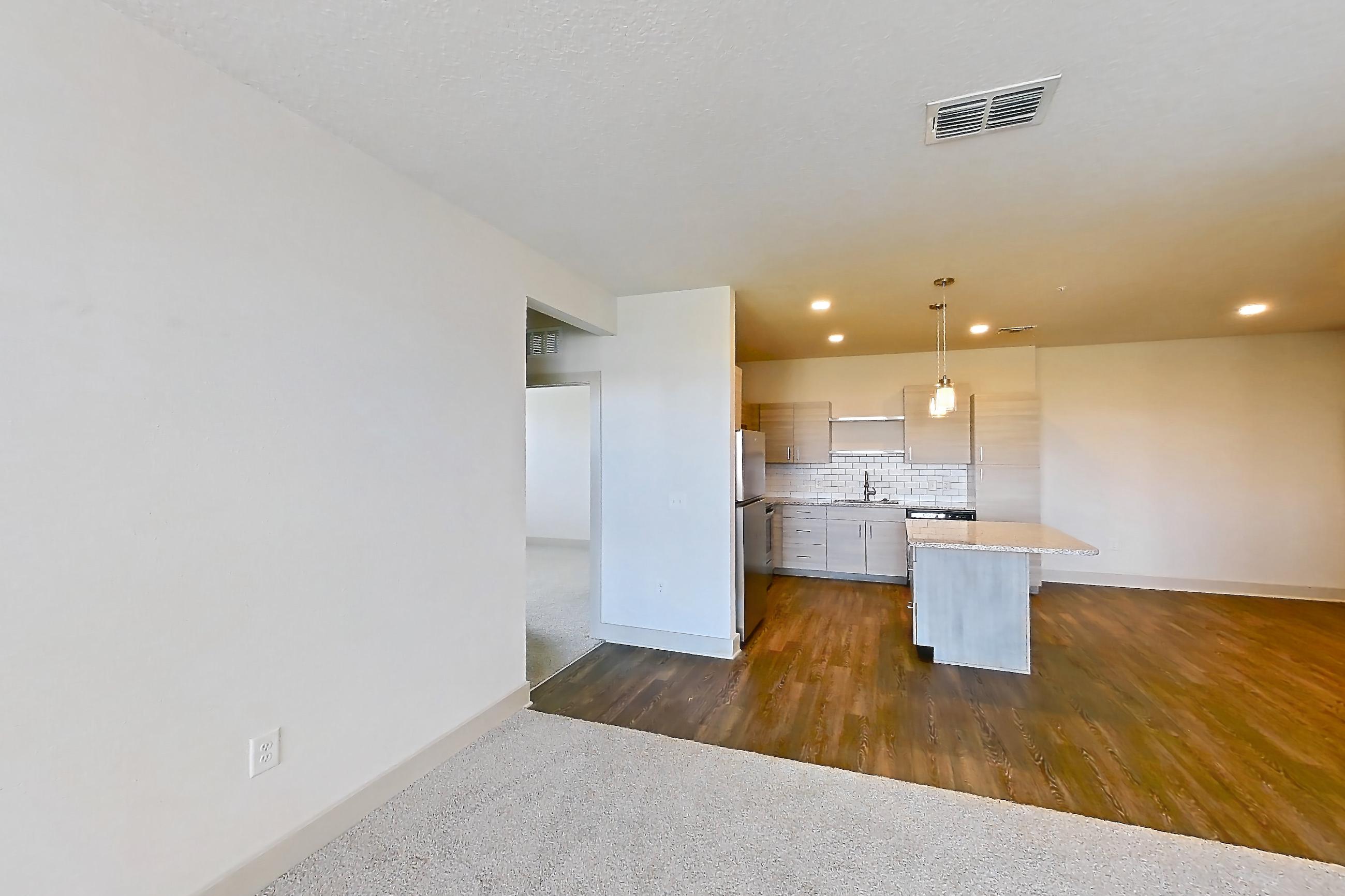 Living room with dark carpet, refrigerator, and stainless steel appliances, Apartment 114-301 at Domain