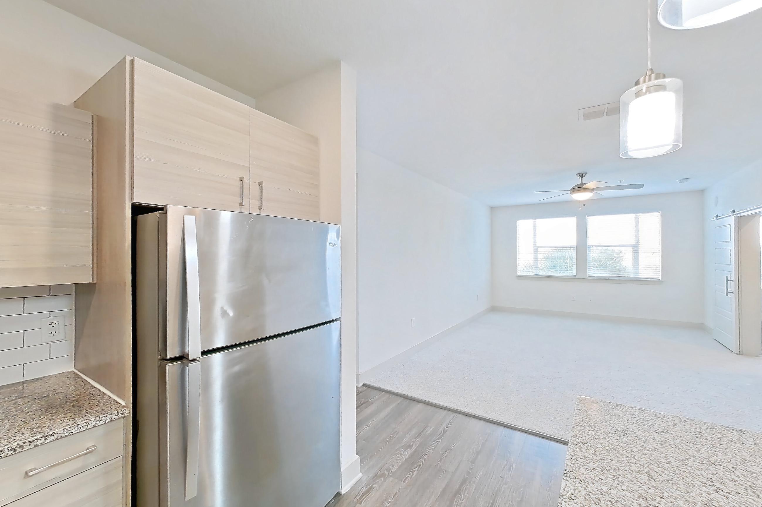 Kitchen with dishwasher, electric range, light countertops, light stone countertops, light wood-finish flooring, oven/range, refrigerator, and stainless steel appliances, Apartment 116-302 at Domain