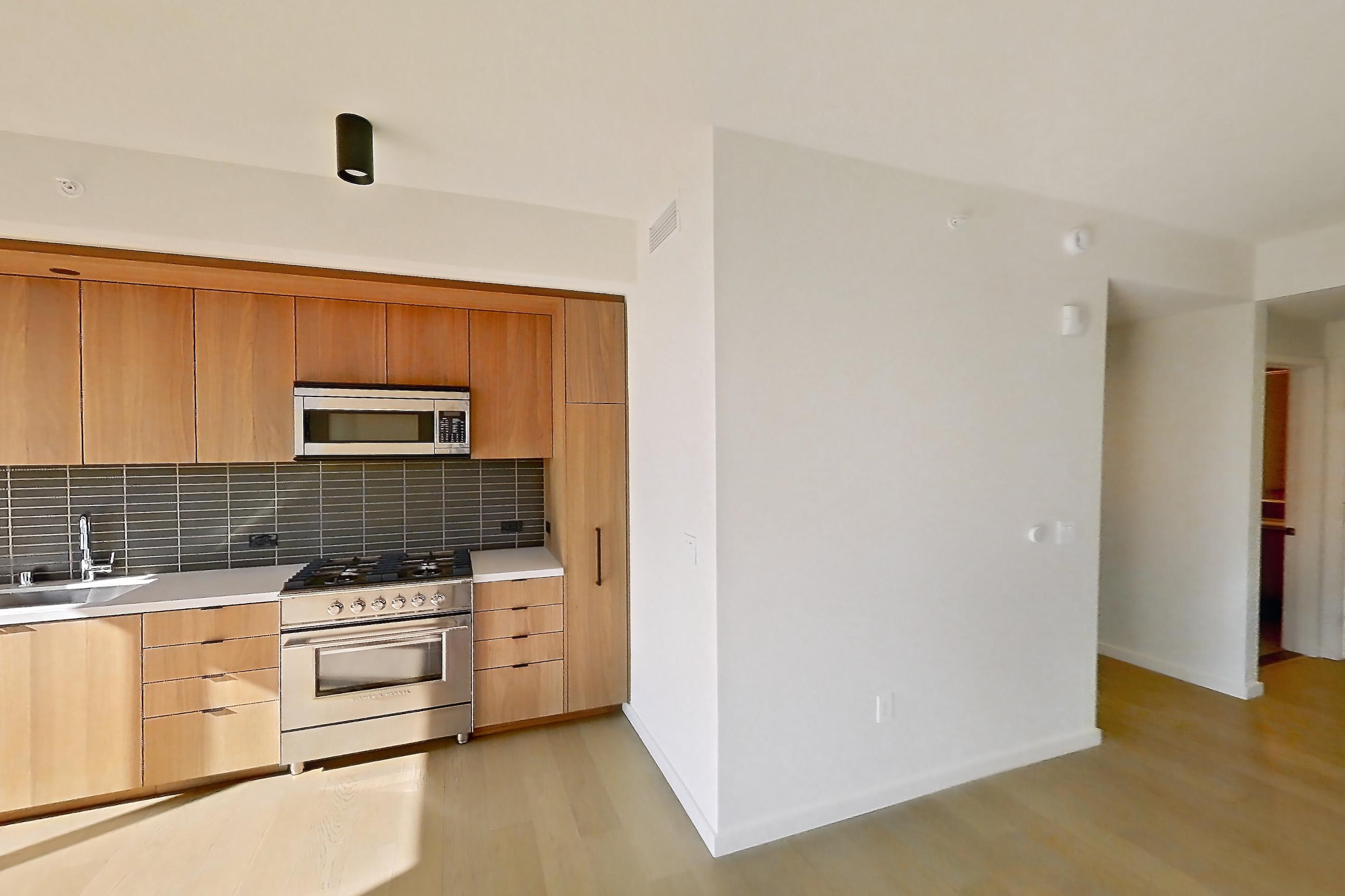 Living room with city view and light wood-finish flooring, Apartment B-3216 at Beaudry