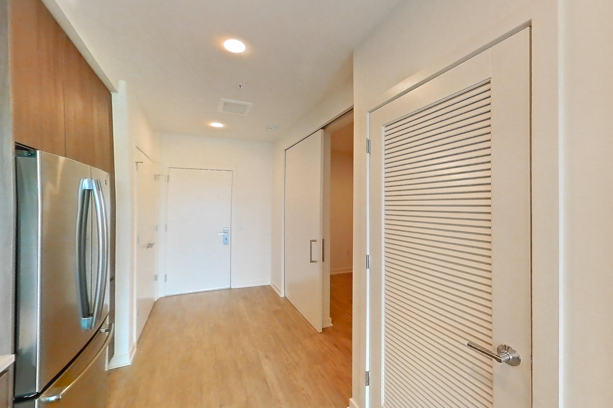Kitchen with dishwasher, electric range, light countertops, light stone countertops, light wood-finish flooring, microwave, oven/range, refrigerator, and stainless steel appliances, Apartment 2507 at Platform (VA)