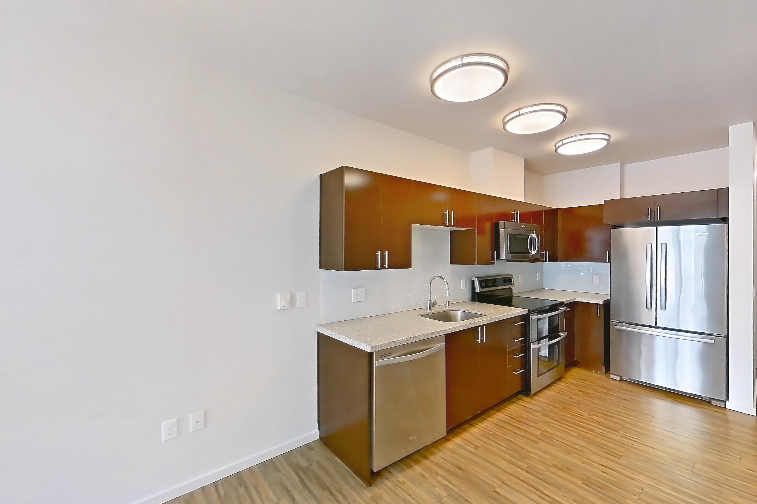 Living space with dishwasher, light stone countertops, light wood-finish flooring, and stainless steel appliances, Unit L708 at Union SLU