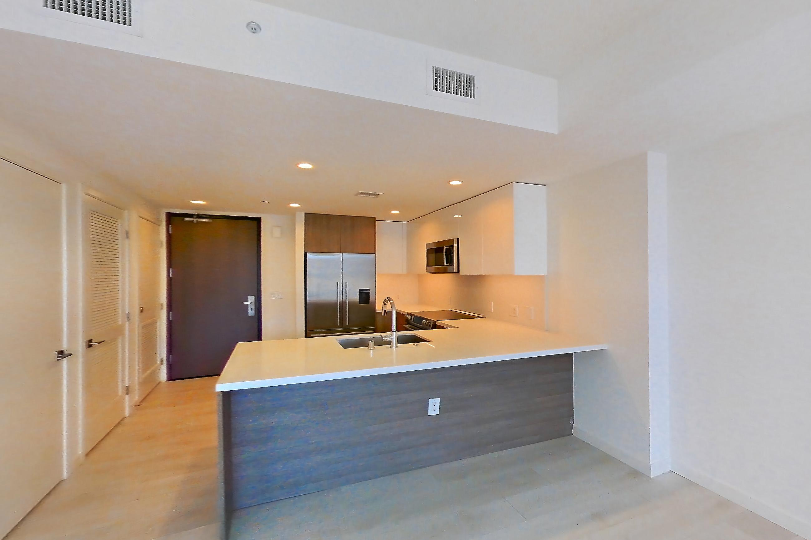 Living room with light stone countertops, light wood-finish flooring, oven/range, refrigerator, stainless steel appliances, and water & ice dispenser, Apartment 0609 at Atelier