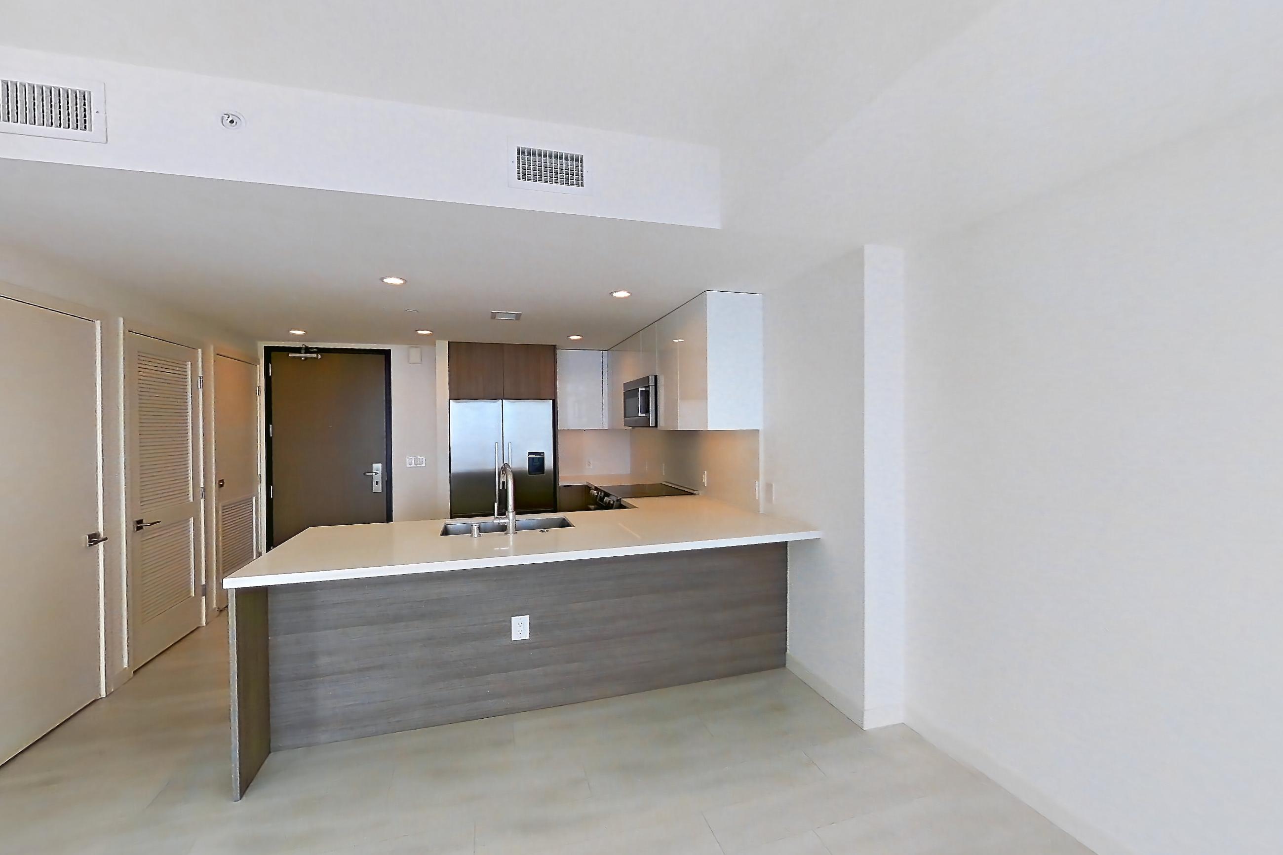 Living room with city view, electric cooktop, light stone countertops, and light wood-finish flooring, Apartment 2807 at Atelier