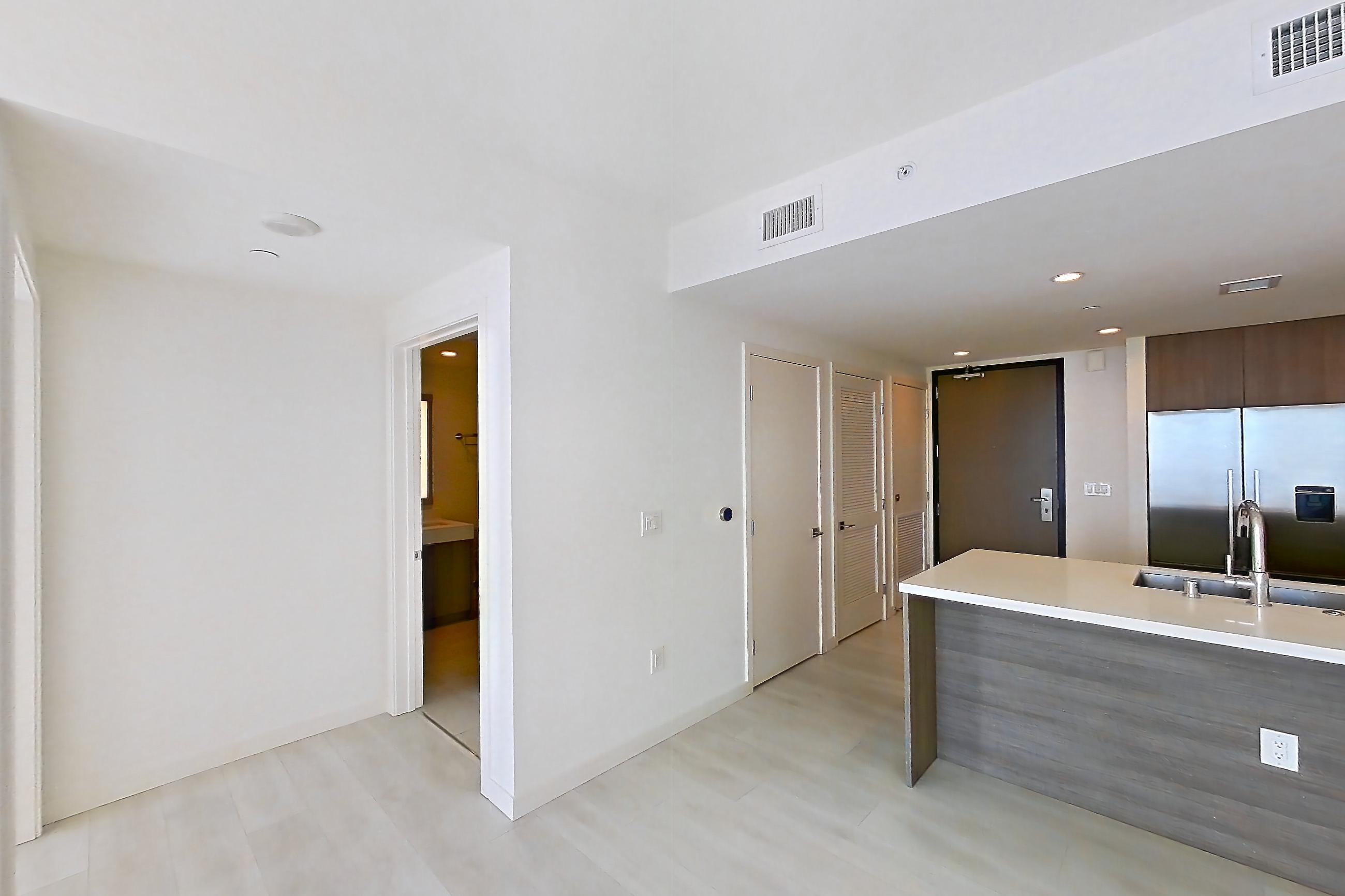Living room with city view, electric cooktop, light stone countertops, and light wood-finish flooring, Apartment 2807 at Atelier