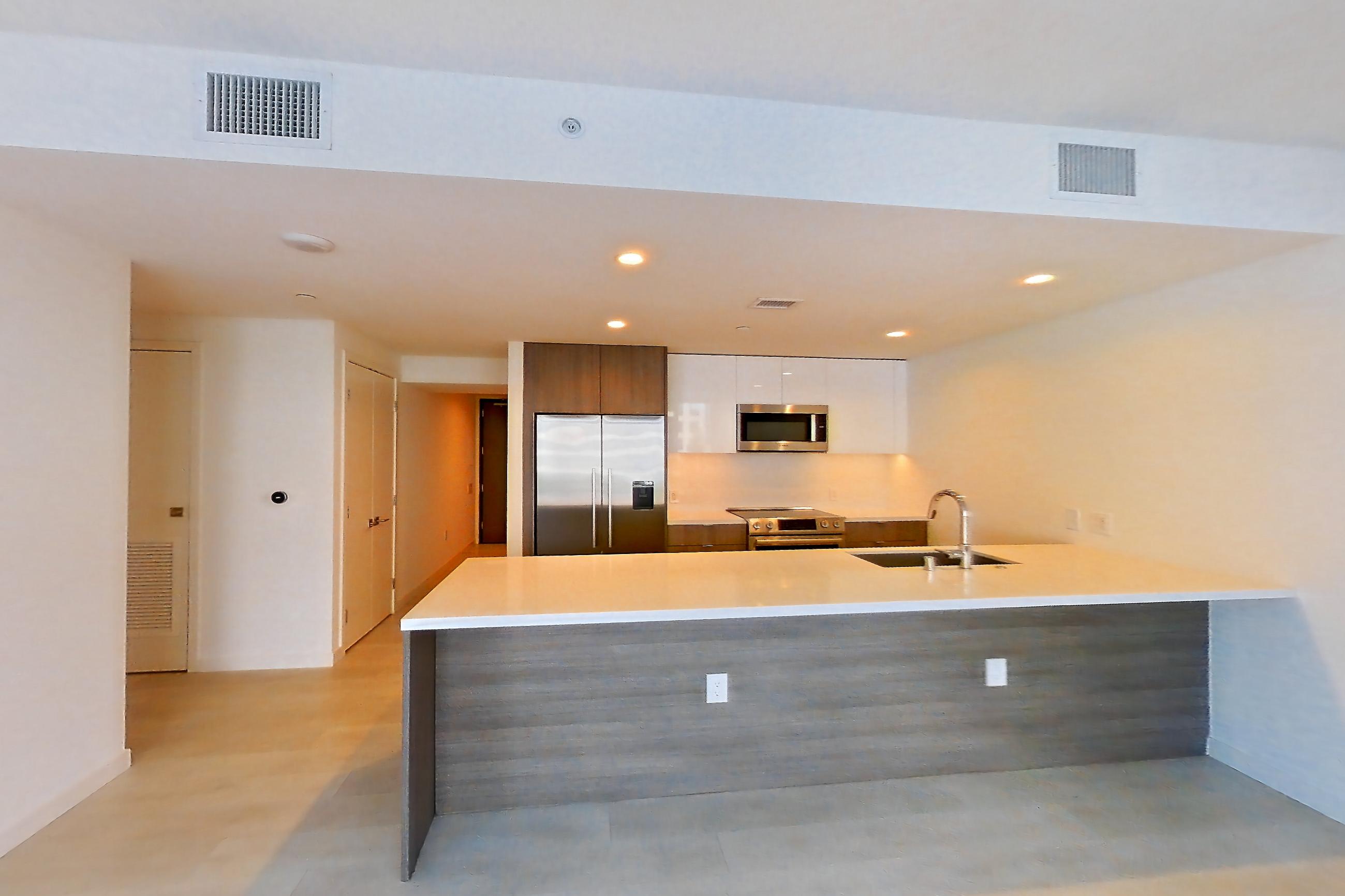 Living room with electric range, light stone countertops, oven/range, refrigerator, stainless steel appliances, and water & ice dispenser, Apartment 0608 at Atelier