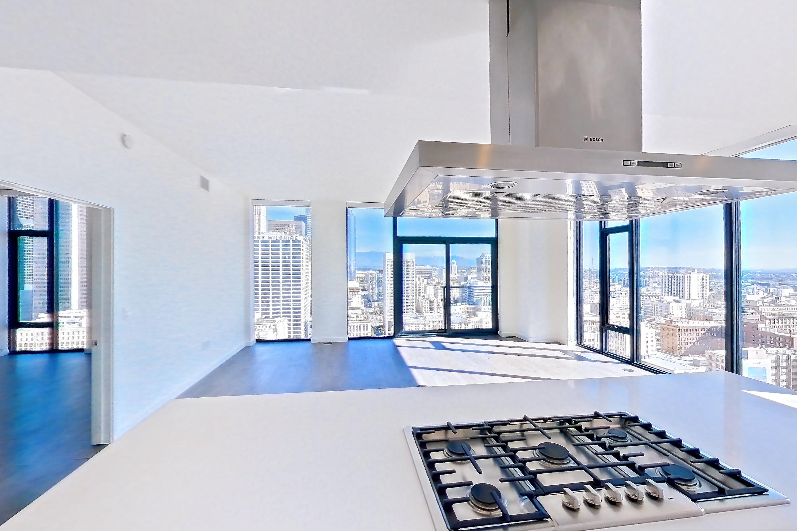 Kitchen with cooktop, dark wood-finish flooring, gas cooktop, light stone countertops, oven/range, stainless steel appliances, and wood-finish flooring, Apartment 3001 at Atelier