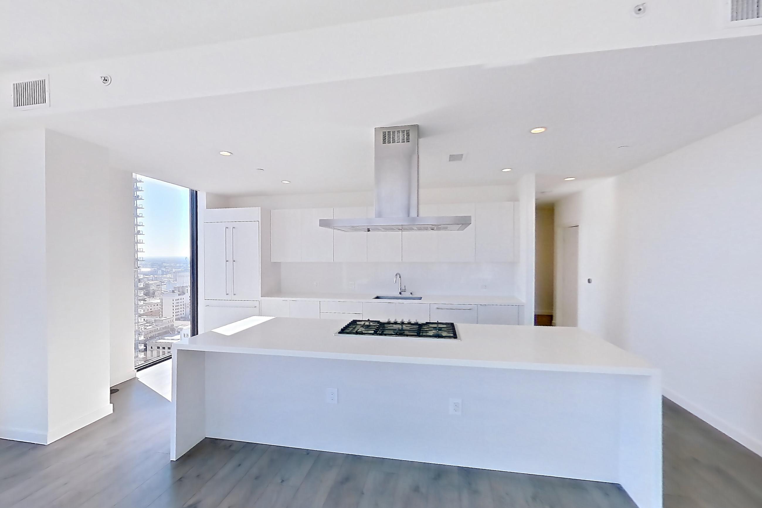 Living room with cooktop, dark wood-finish flooring, gas cooktop, kitchen island, light stone countertops, range hood, stainless steel appliances, and wood-finish flooring, Apartment 3001 at Atelier
