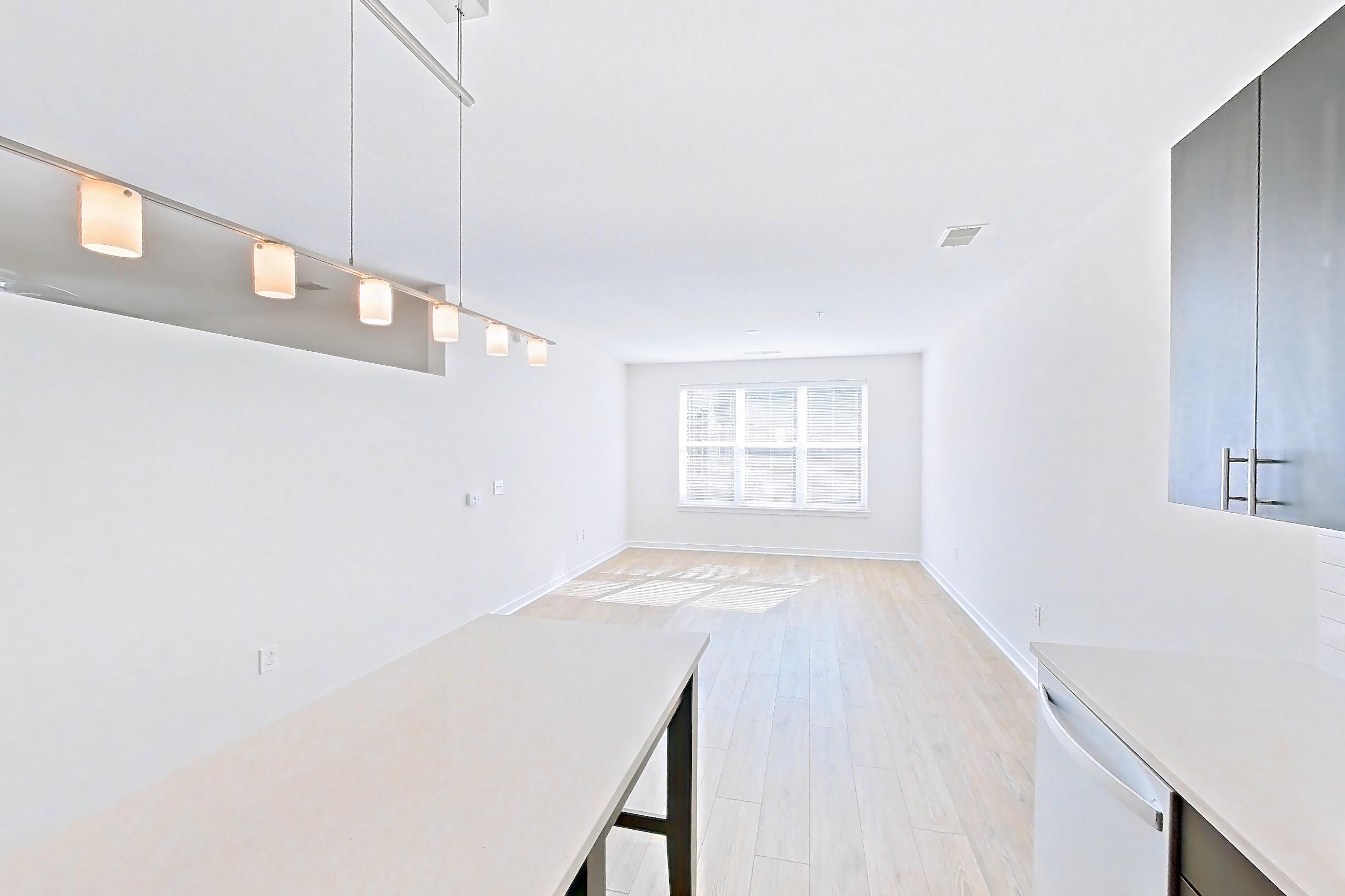 Kitchen with dishwasher, electric range, light countertops, light wood-finish flooring, microwave, oven/range, refrigerator, stainless steel appliances, and white appliances, Apartment 1-110 at The Parker at Huntington Metro