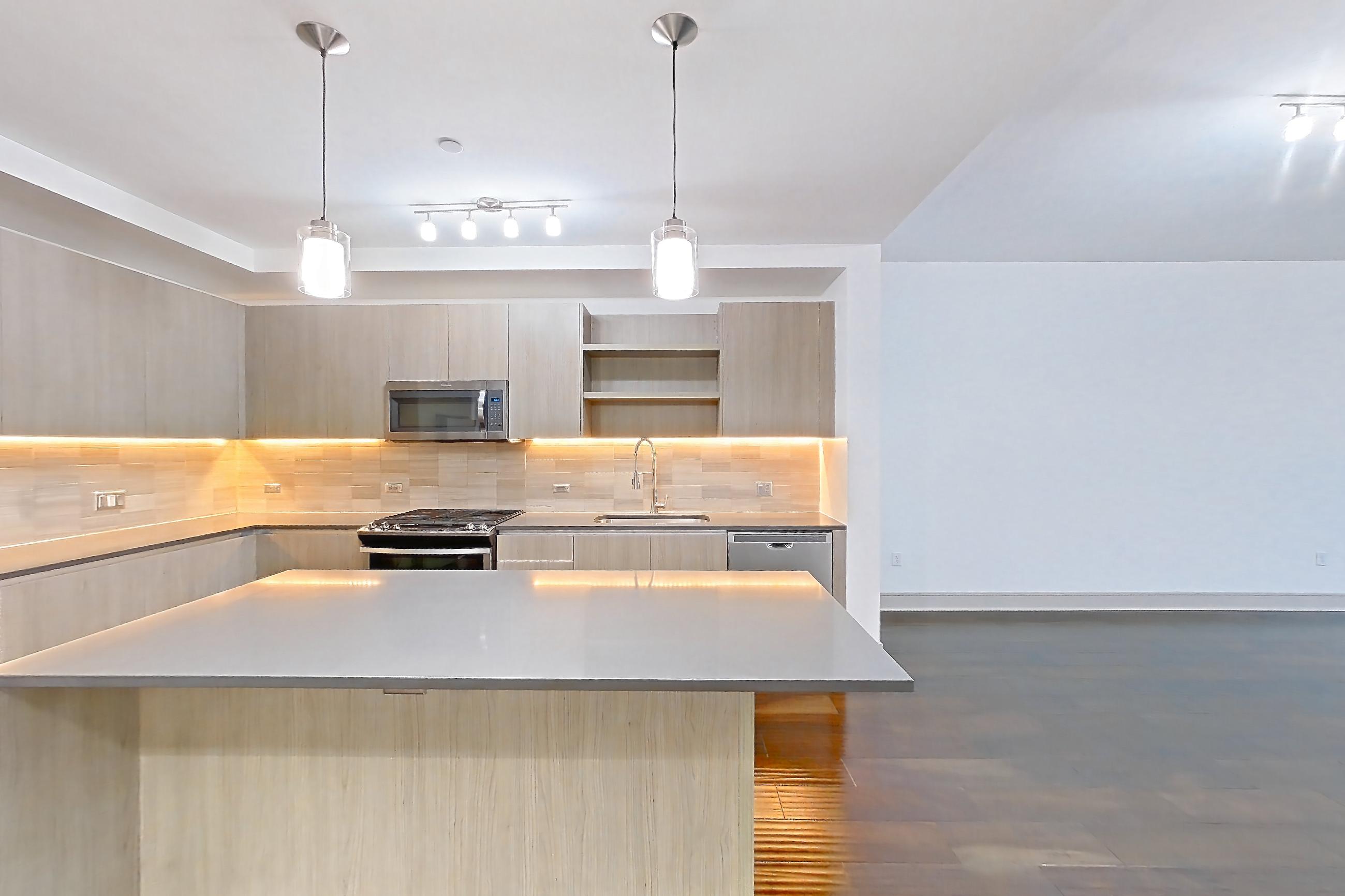 Dining room with dark wood-finish flooring, dishwasher, gas range, light countertops, oven/range, refrigerator, stainless steel appliances, water & ice dispenser, and wood-finish flooring, Apartment 1401 at Cortland Museum District