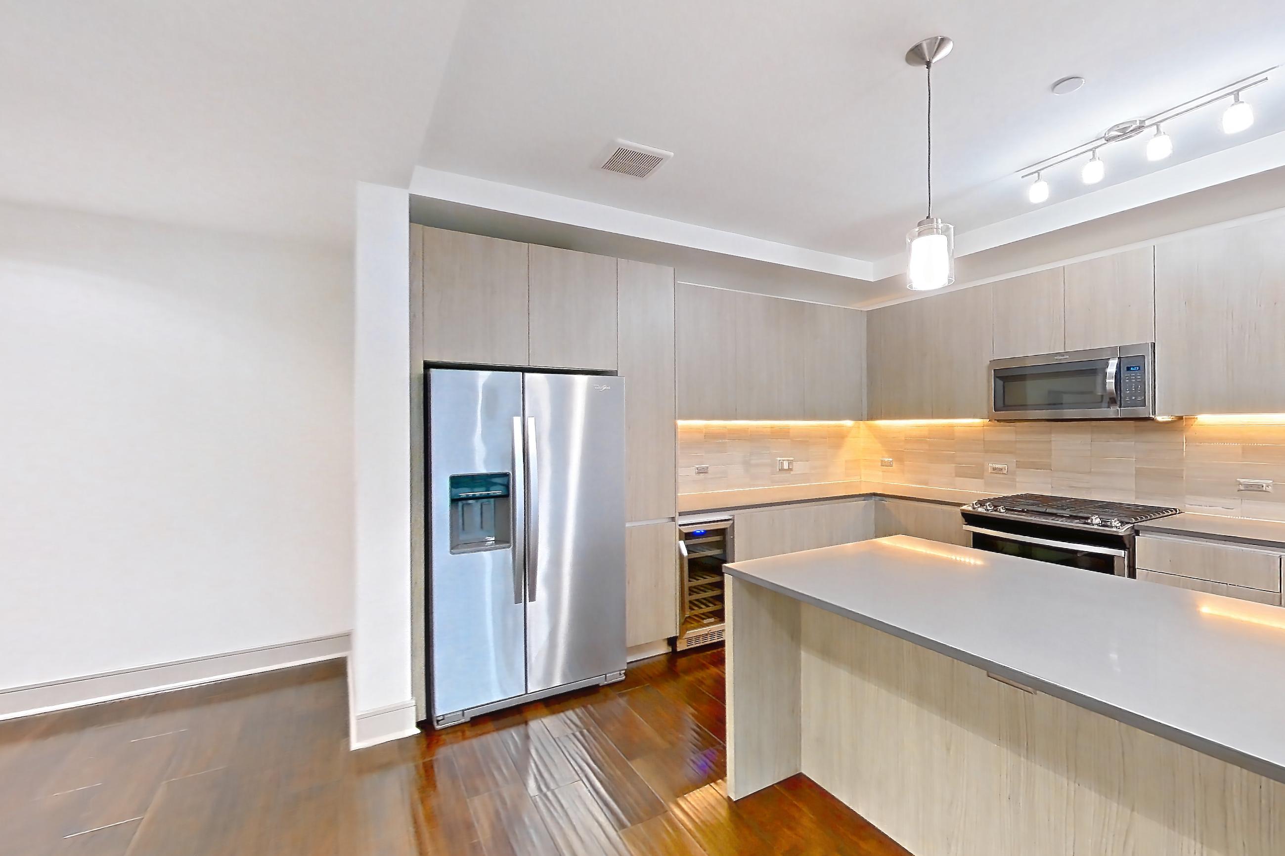 Dining room with dark wood-finish flooring, dishwasher, gas range, light countertops, oven/range, refrigerator, stainless steel appliances, water & ice dispenser, and wood-finish flooring, Apartment 1401 at Cortland Museum District