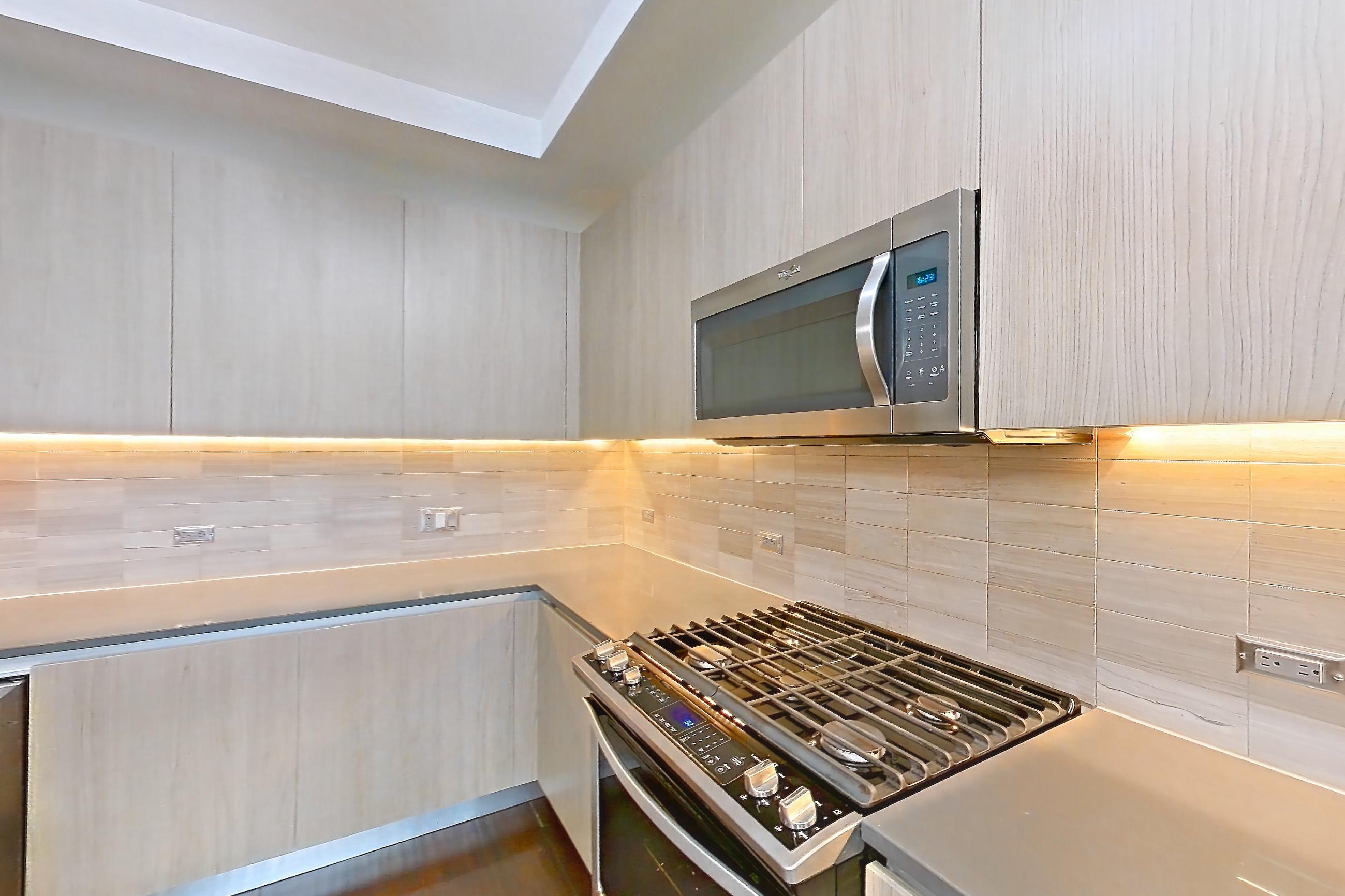 Kitchen with dark wood-finish flooring, gas range, oven/range, stainless steel appliances, and wood-finish flooring, Apartment 1401 at Cortland Museum District