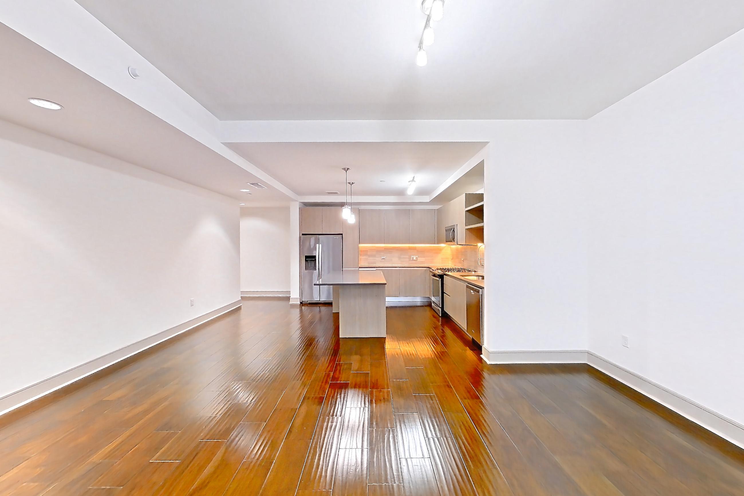 Living room with dark wood-finish flooring, gas range, oven/range, refrigerator, and stainless steel appliances, Apartment 1401 at Cortland Museum District