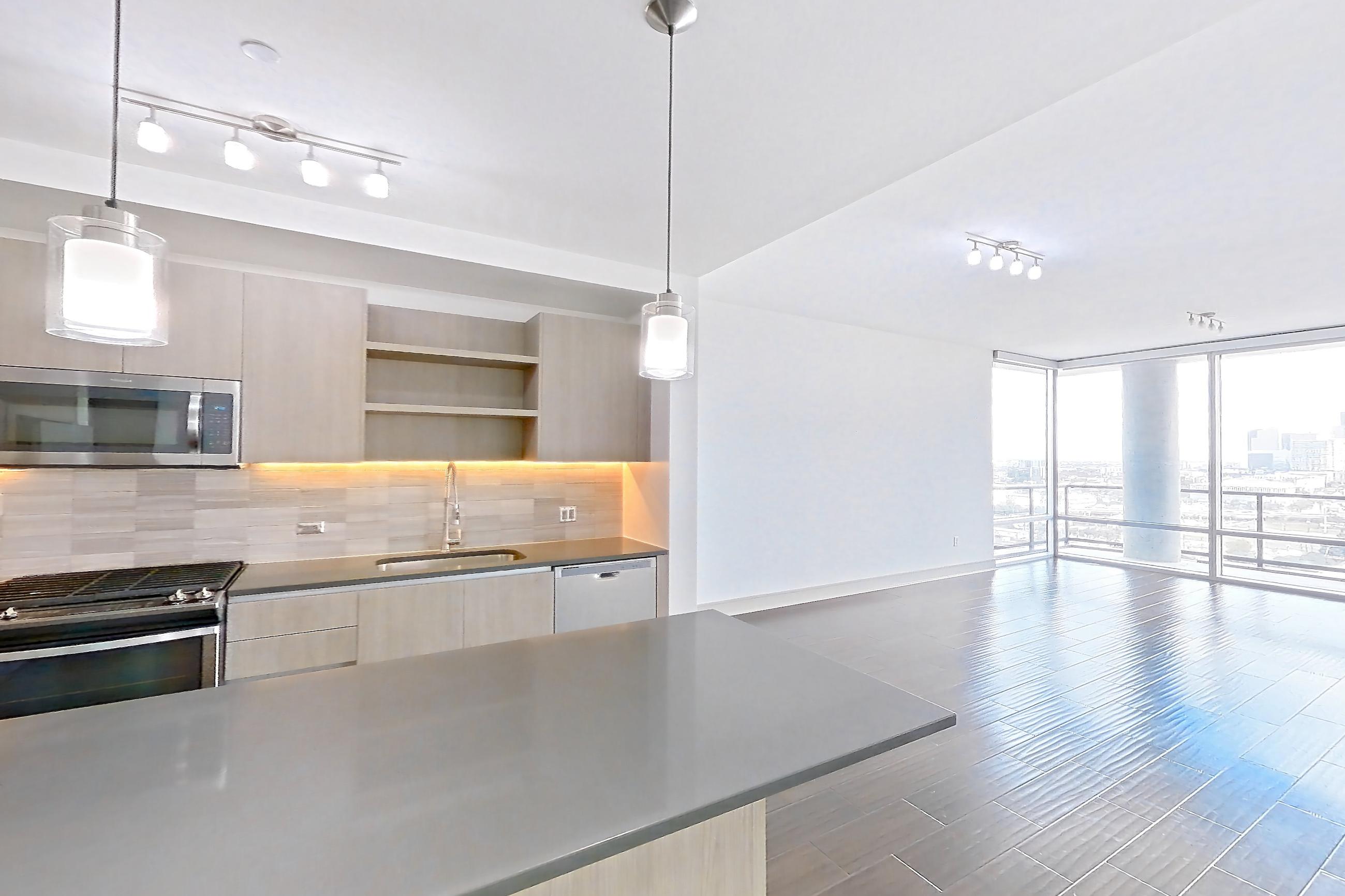 Kitchen space with dark countertops, dark wood-finish flooring, gas range, oven/range, stainless steel appliances, and wood-finish flooring, Apartment 1801 at Cortland Museum District