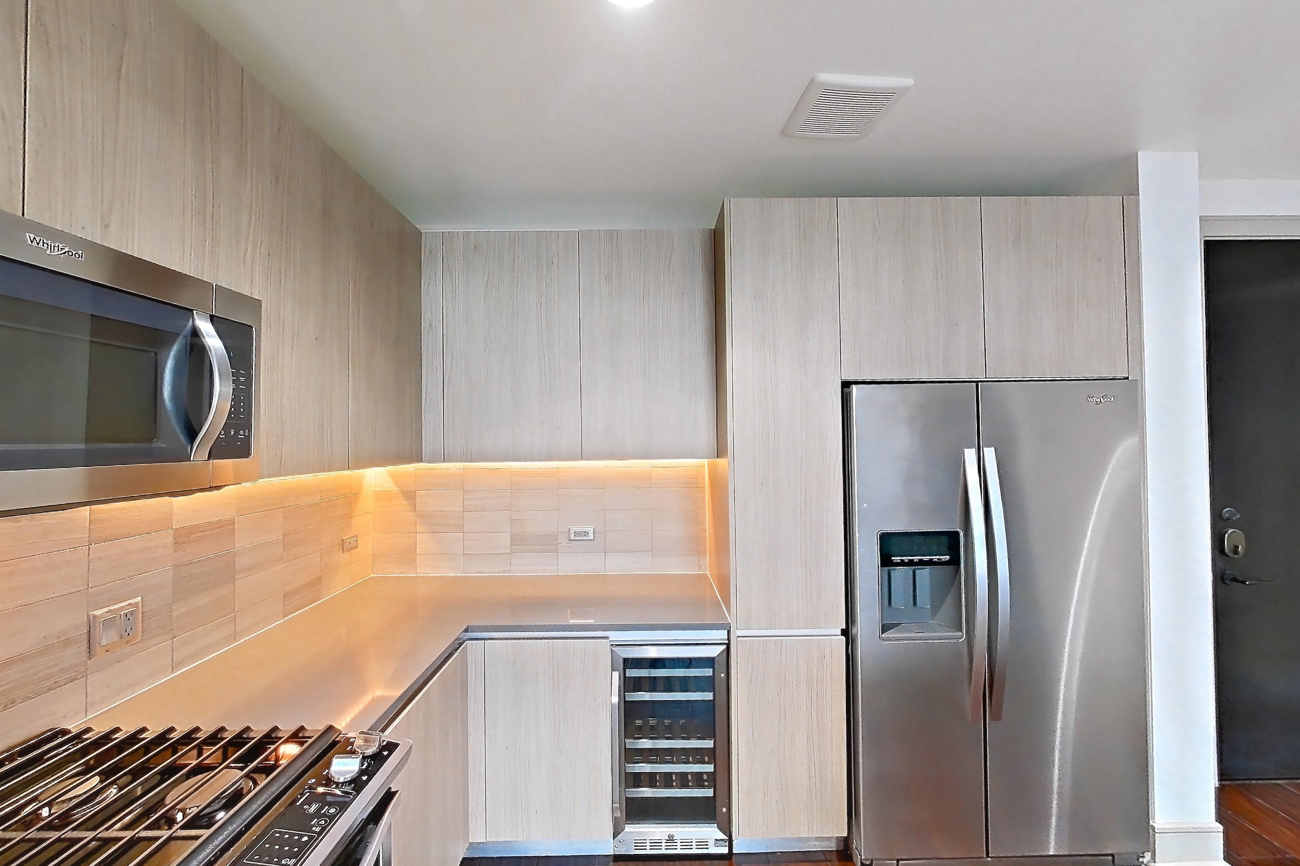 Kitchen with dark wood-finish flooring, gas range, light countertops, oven/range, refrigerator, stainless steel appliances, and water & ice dispenser, Apartment 1603 at Cortland Museum District