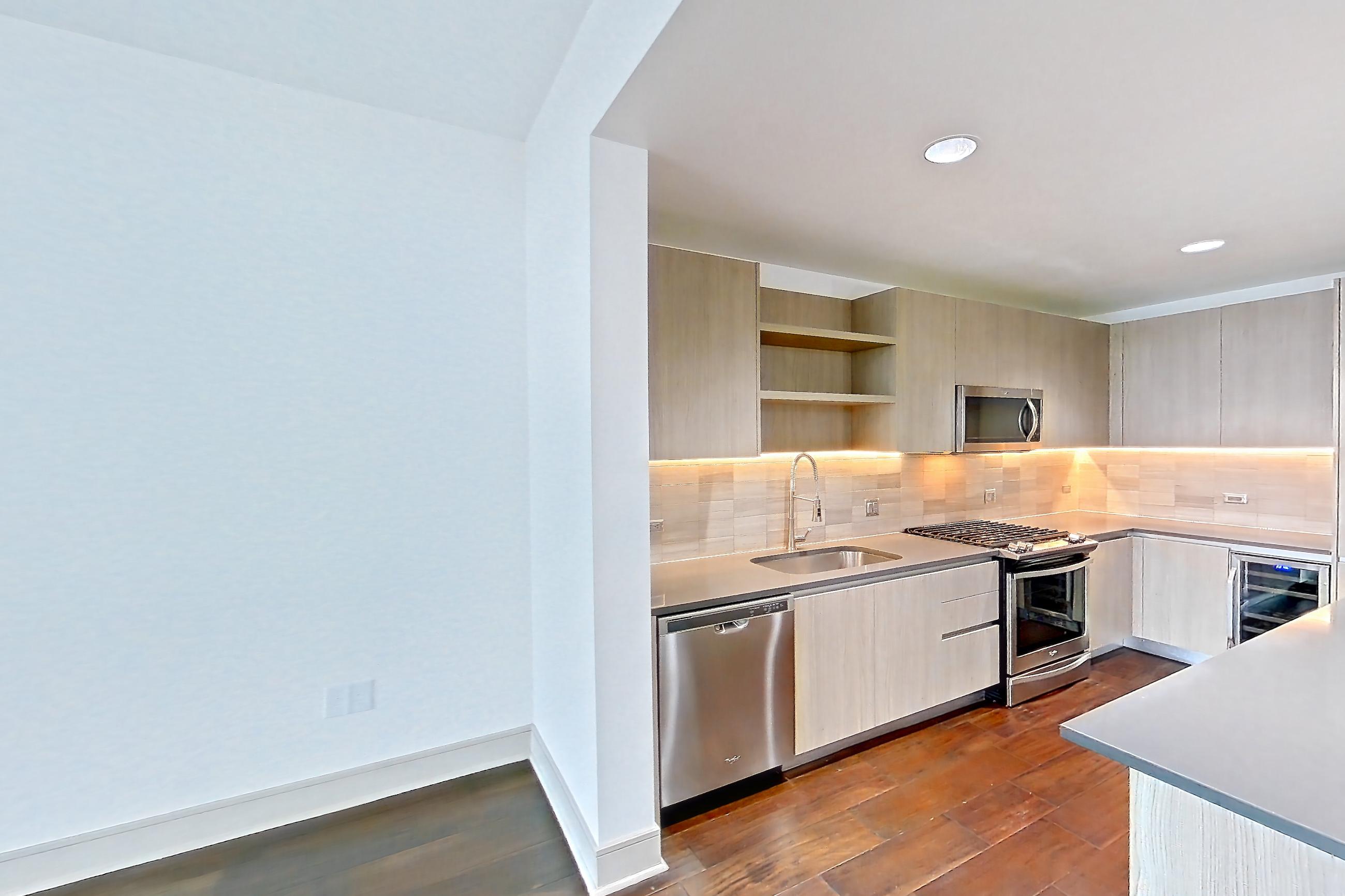 Living space with dark wood-finish flooring, dishwasher, and stainless steel appliances, Apartment 1603 at Cortland Museum District