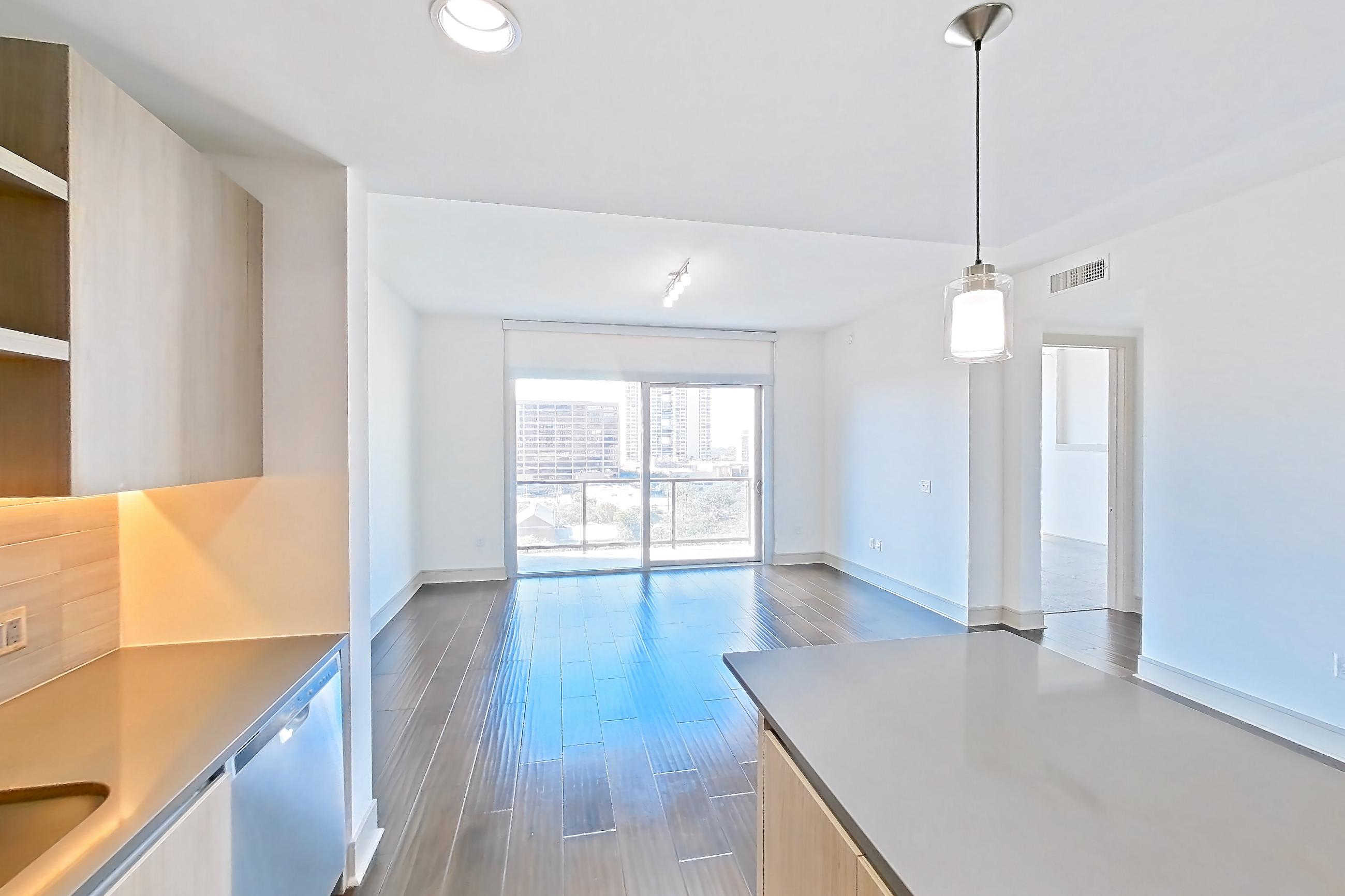 Kitchen with dark wood-finish flooring, gas range, light countertops, microwave, oven/range, refrigerator, stainless steel appliances, and water & ice dispenser, Apartment 1007 at Cortland Museum District