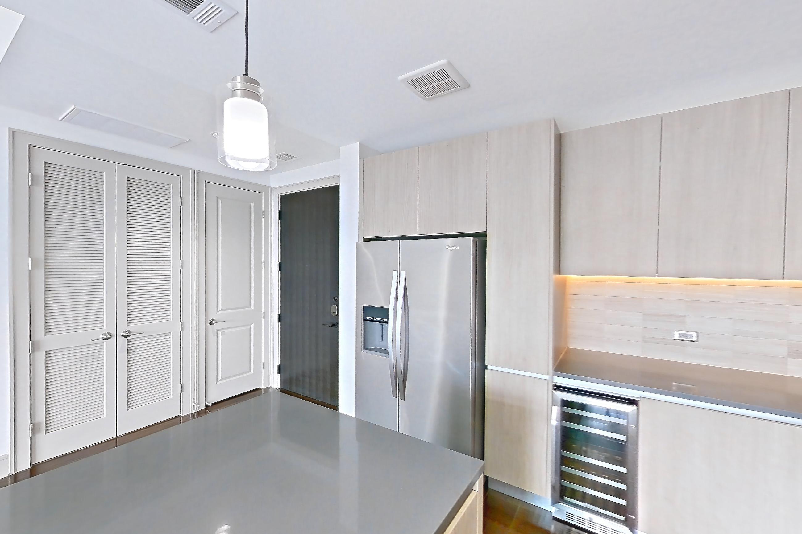 Kitchen with dark wood-finish flooring, dishwasher, gas range, oven/range, refrigerator, stainless steel appliances, and water & ice dispenser, Apartment 1307 at Cortland Museum District