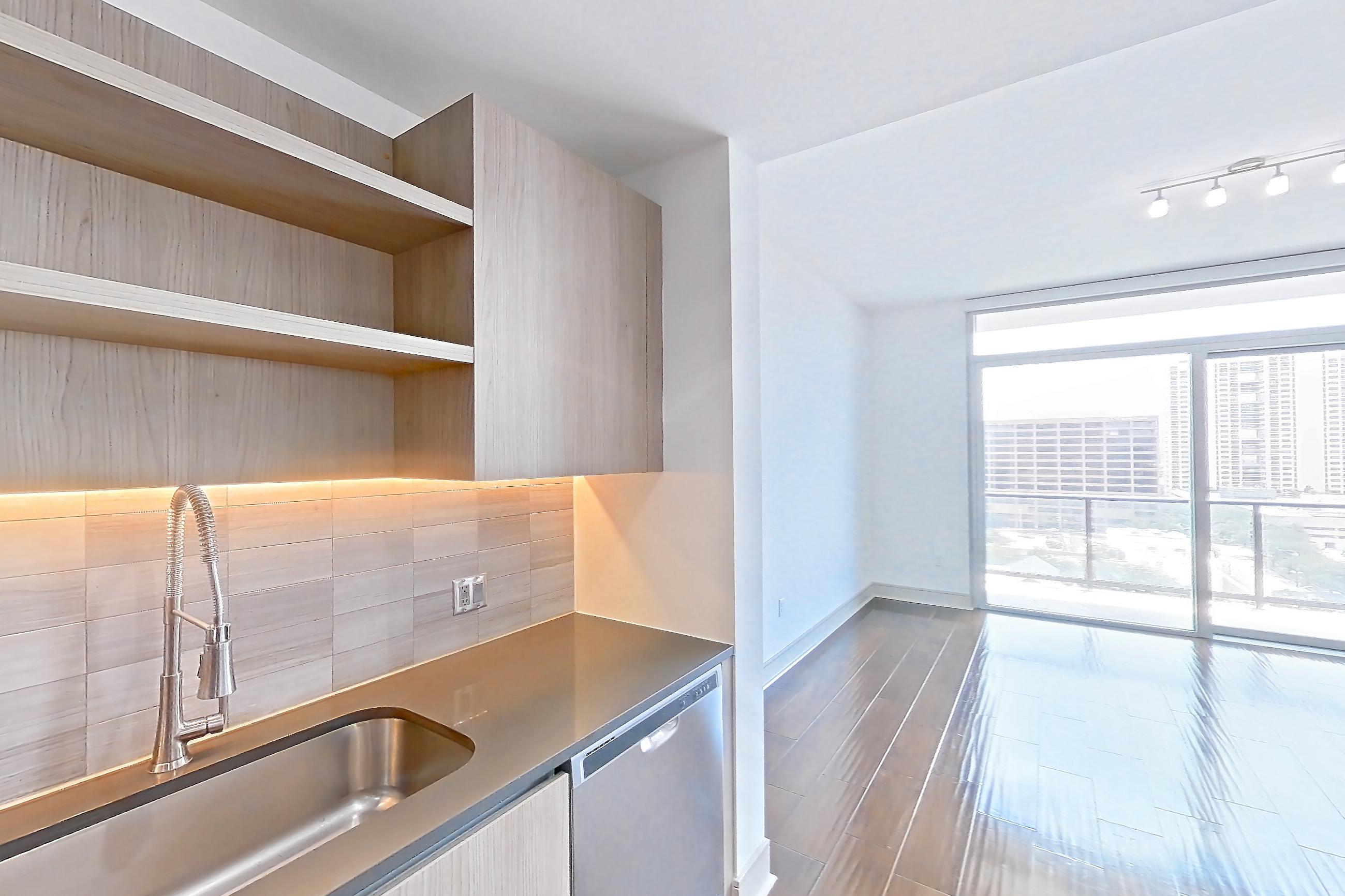 Kitchen with dark wood-finish flooring, dishwasher, gas range, oven/range, refrigerator, stainless steel appliances, and water & ice dispenser, Apartment 1307 at Cortland Museum District